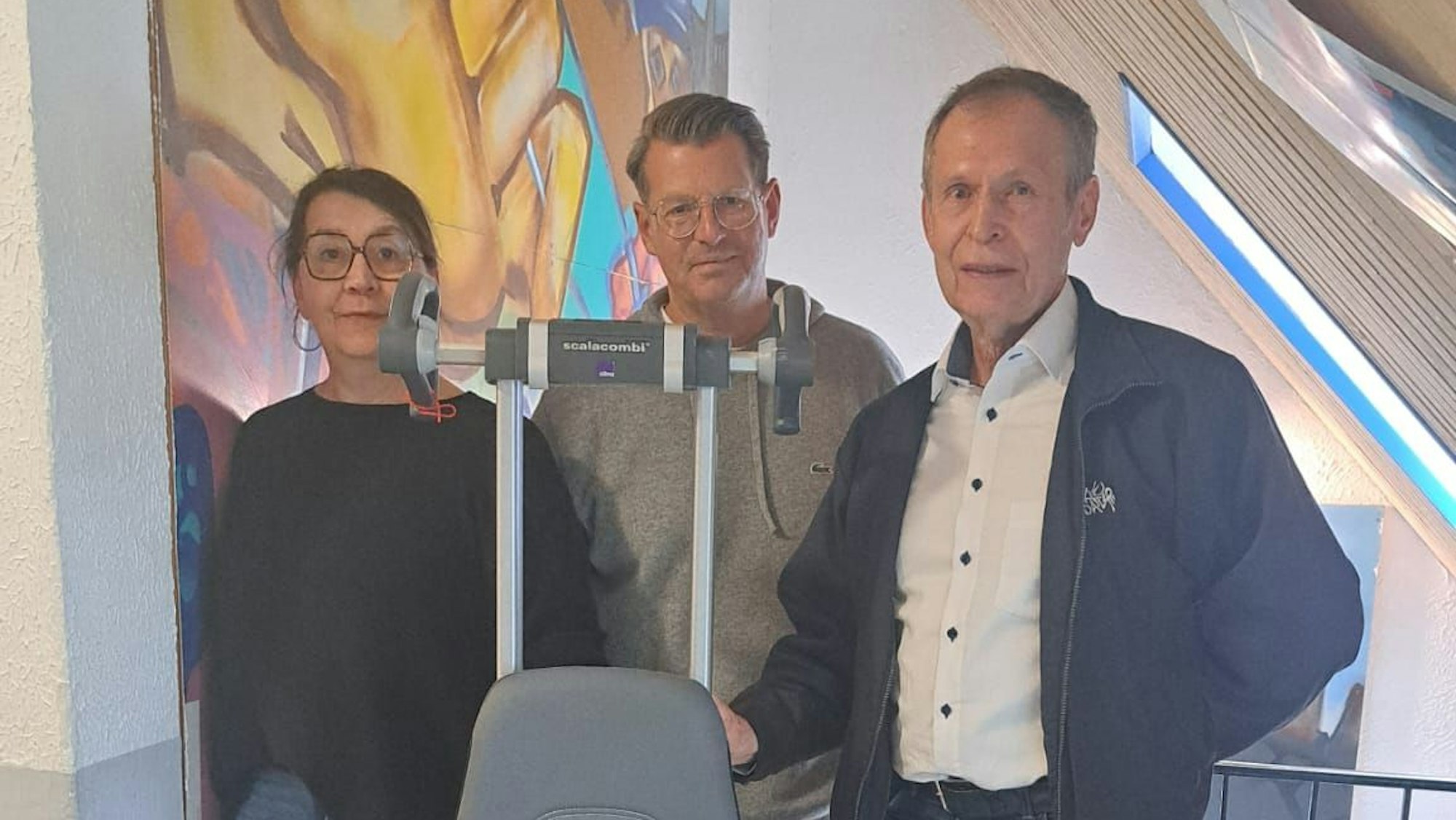 Eine Frau und zwei Männer stehen nebeneinander.