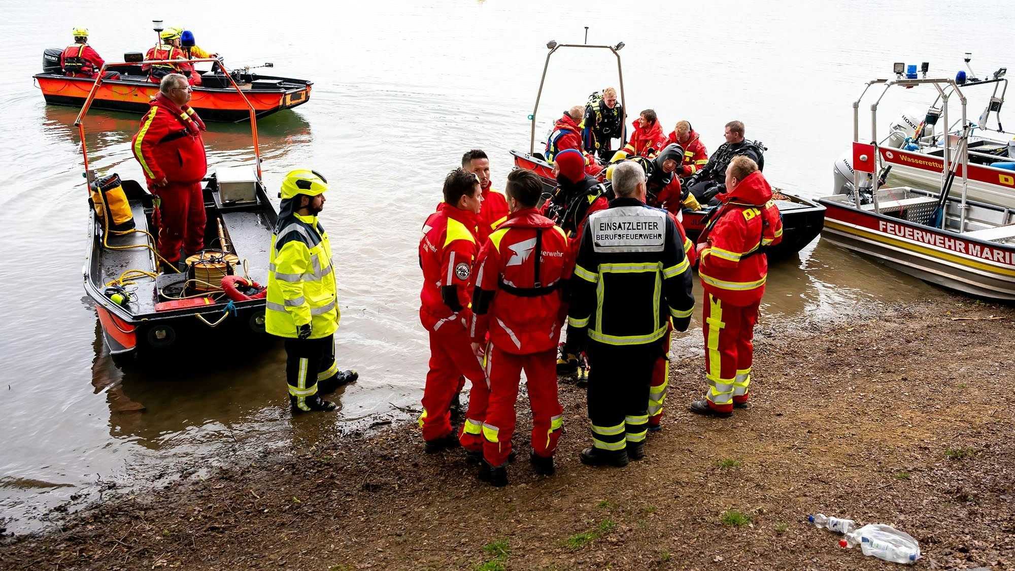 Uniformierte Männer mit Booten am Ufer der Talsperre.