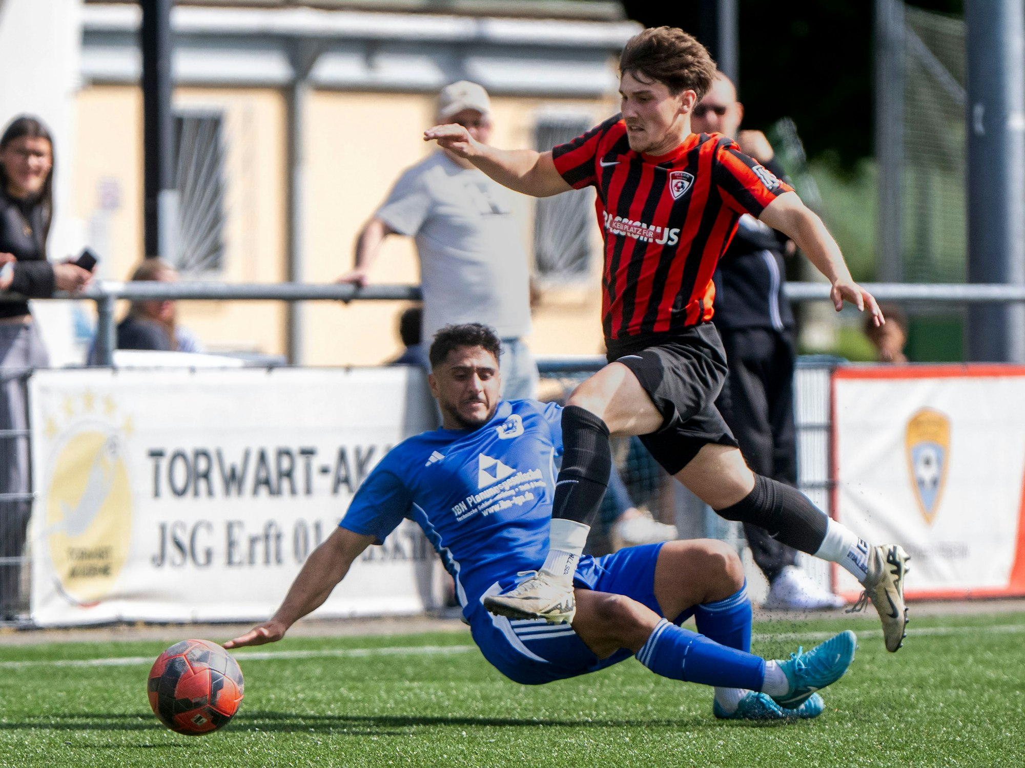 Das Bild zeigt, wie Woywod sich den Ball an seinem Gegenspieler vorbei gelegt hat und über dessen Beine springt.