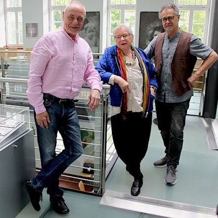 Die drei Vorstandsmitglieder lehnen sich an die Schaukästen in einem Ausstellungsraum des Kunst-Forums in der Alten Schule in Gemünd.