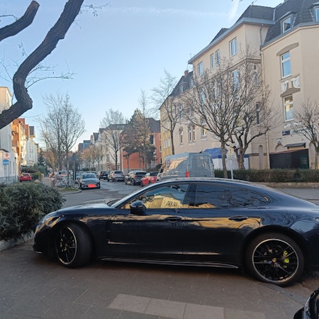 Ein Auto steht auf einem Gehweg, so dass Fußgänger die Straße nicht überqueren können.
