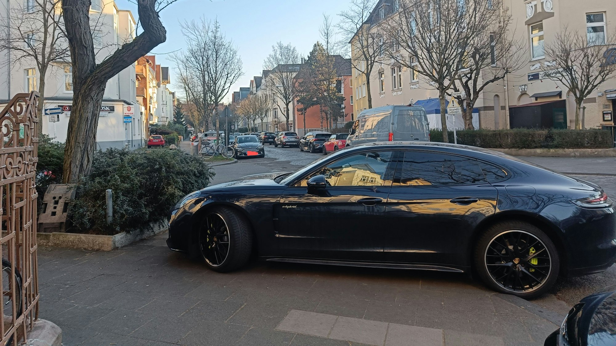 Ein Auto steht auf einem Gehweg, so dass Fußgänger die Straße nicht überqueren können.