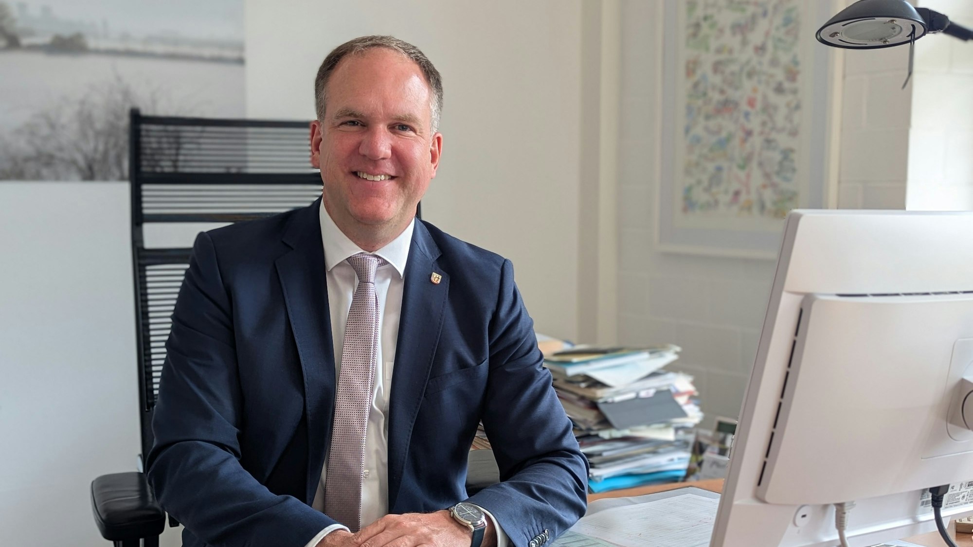 Das Foto zeigt Bürgermeister Dirk Breuer hinter einem Computerbildschirm an seinem Schreibtisch.