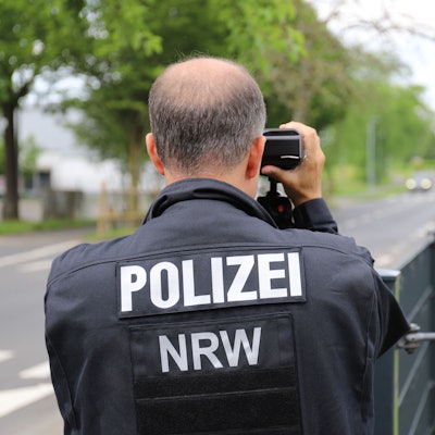 Ein Polizist misst mit einer Laserpistole die Geschwindigkeit von Fahrzeugen, die an der Kastanienschule vorbeifuhren.