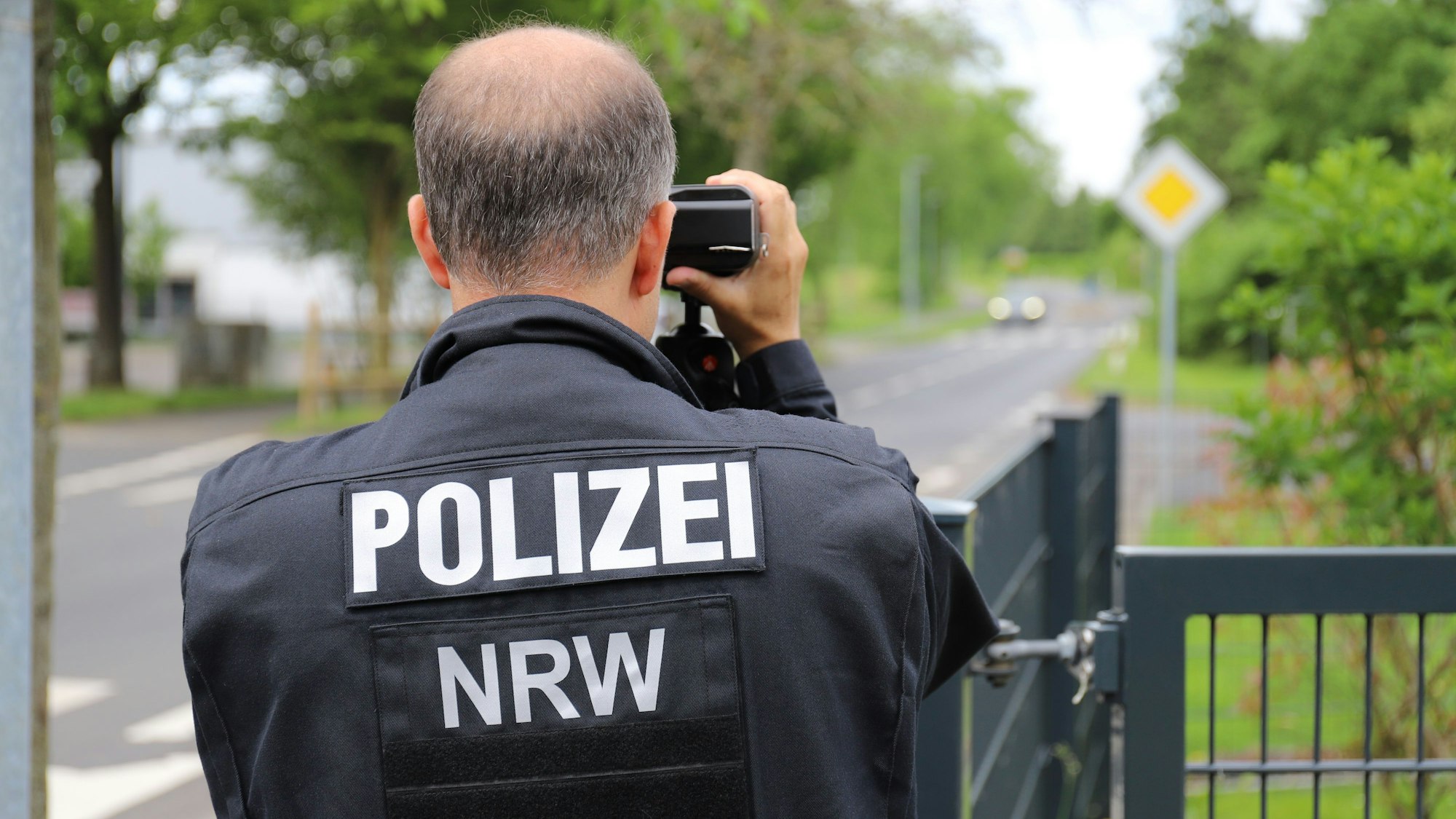 Ein Polizist misst mit einer Laserpistole die Geschwindigkeit von Fahrzeugen, die an der Kastanienschule vorbeifuhren.