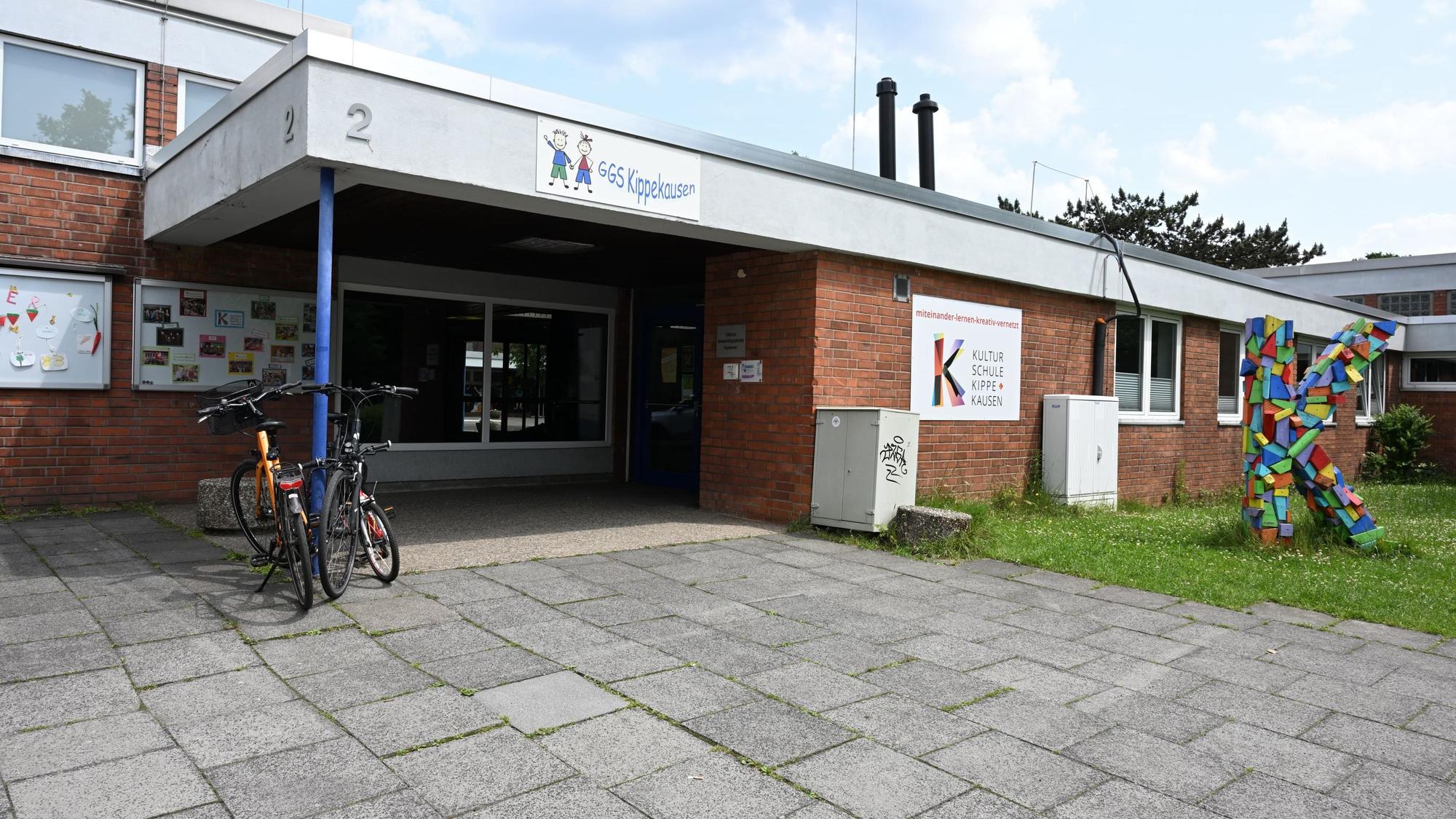 Der Eingang zum Schulgebäude ist zu sehen, davor stehen zwei Fahrräder.