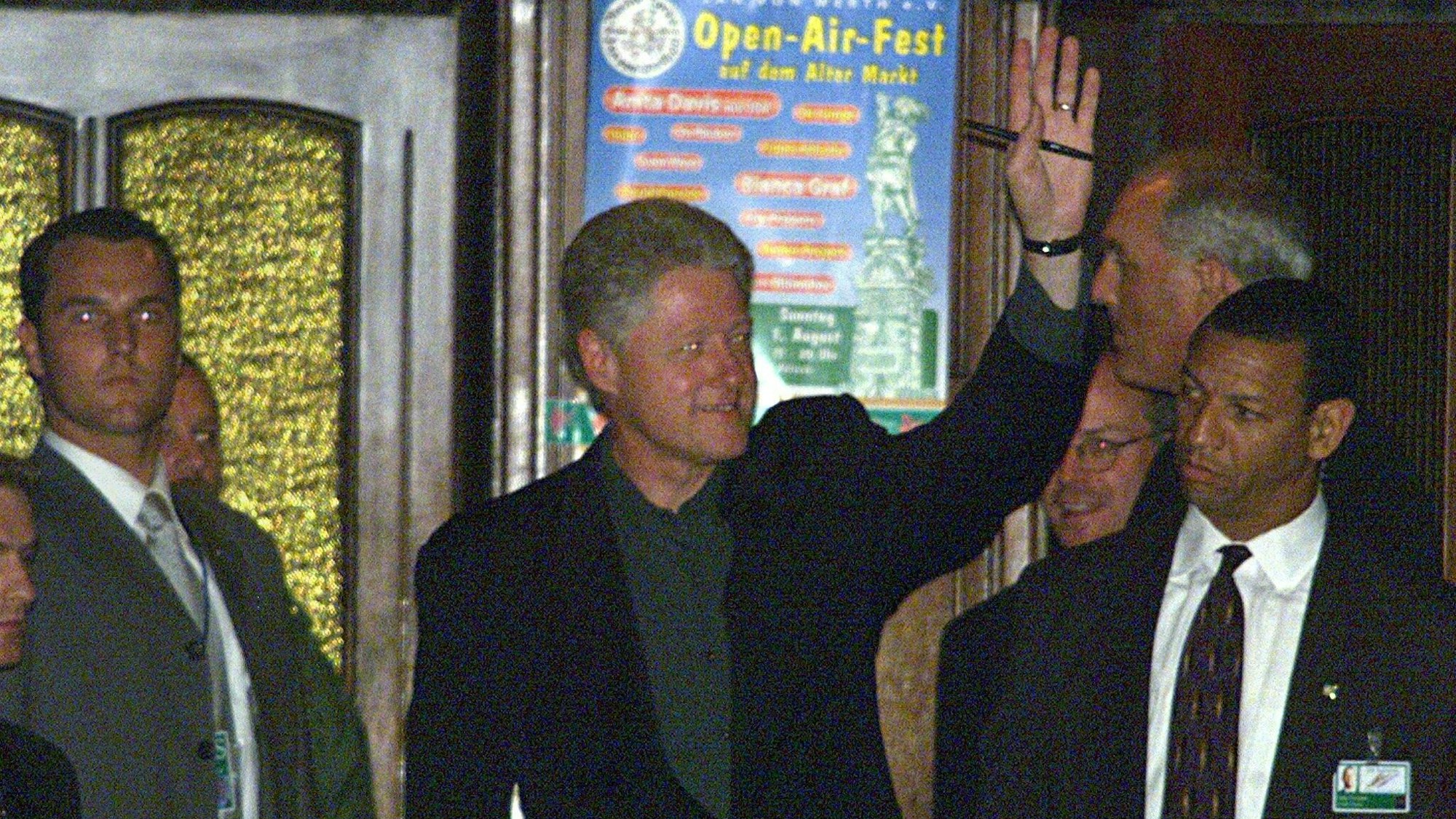 Nach seinem Besuch im Kölner Brauhaus "Zur Malzmühle" winkt US-Präsident Bill Clinton (M) am Donnerstag (17.06.1999) kurz vor Mitternacht den vor dem Lokal wartenden Schaulustigen zu, links und rechts sind Sicherheitsbeamte zu sehen. Clinton nimmt an dem am Freitag (18.06.1999) beginnenden G-8-Gipfel teil, bei dem nach dem Kosovo-Krieg die Flüchtlings-Rückkehr, der Wiederaufbau und die Schaffung von Stabilität auf dem Balkan im Vordergrund stehen wird. dpa (Digitale Fotografie) +++ dpa-Bildfunk +++