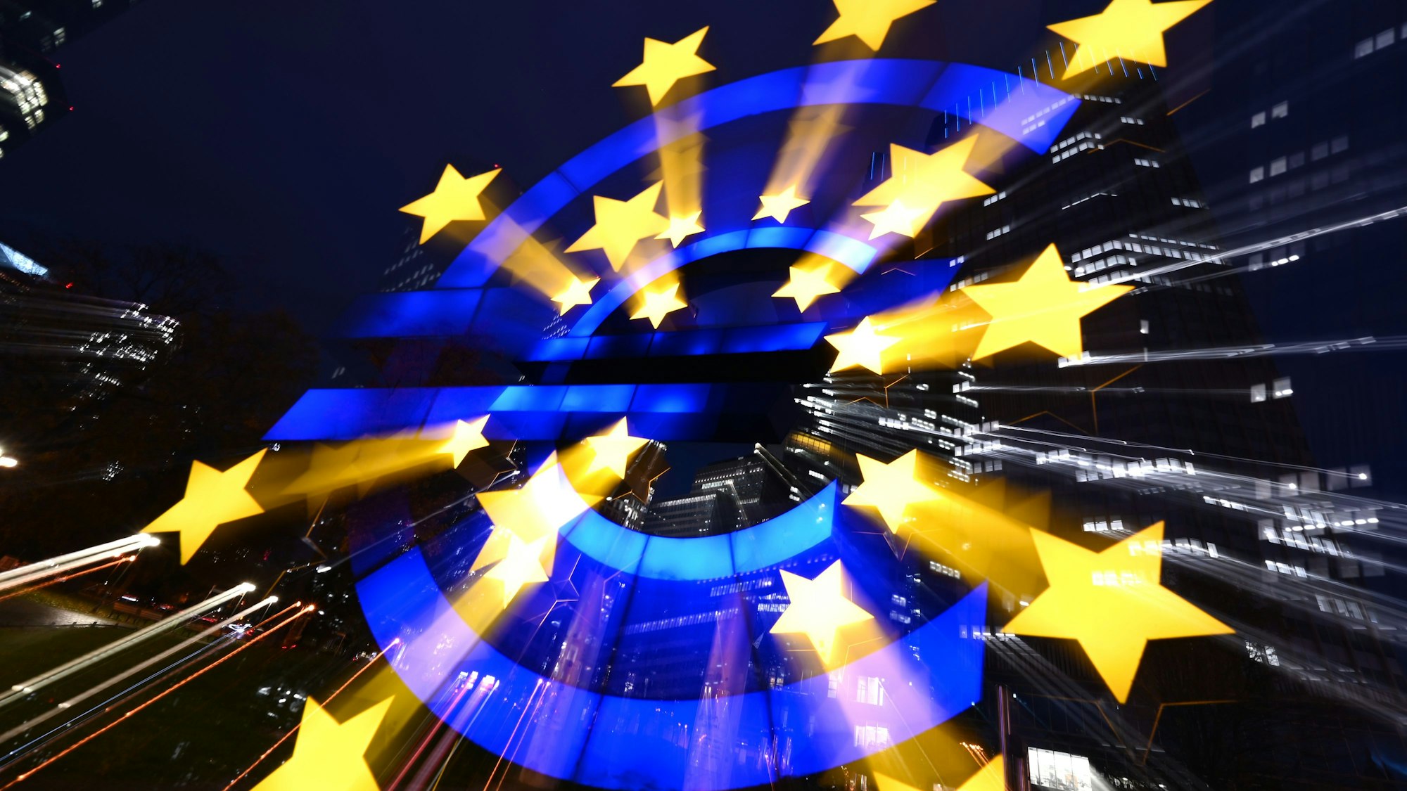 Die Euro-Skulptur des Künstlers Ottmar Hörl leuchtet am Abend vor den Bankentürmen. (Archivbild)
