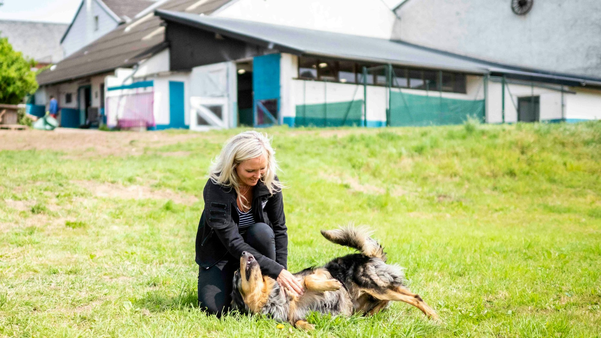 Das Bild zeigt Madeleine Zamani mit einem ihrer Hunde auf dem Gelände der künftigen Huta.