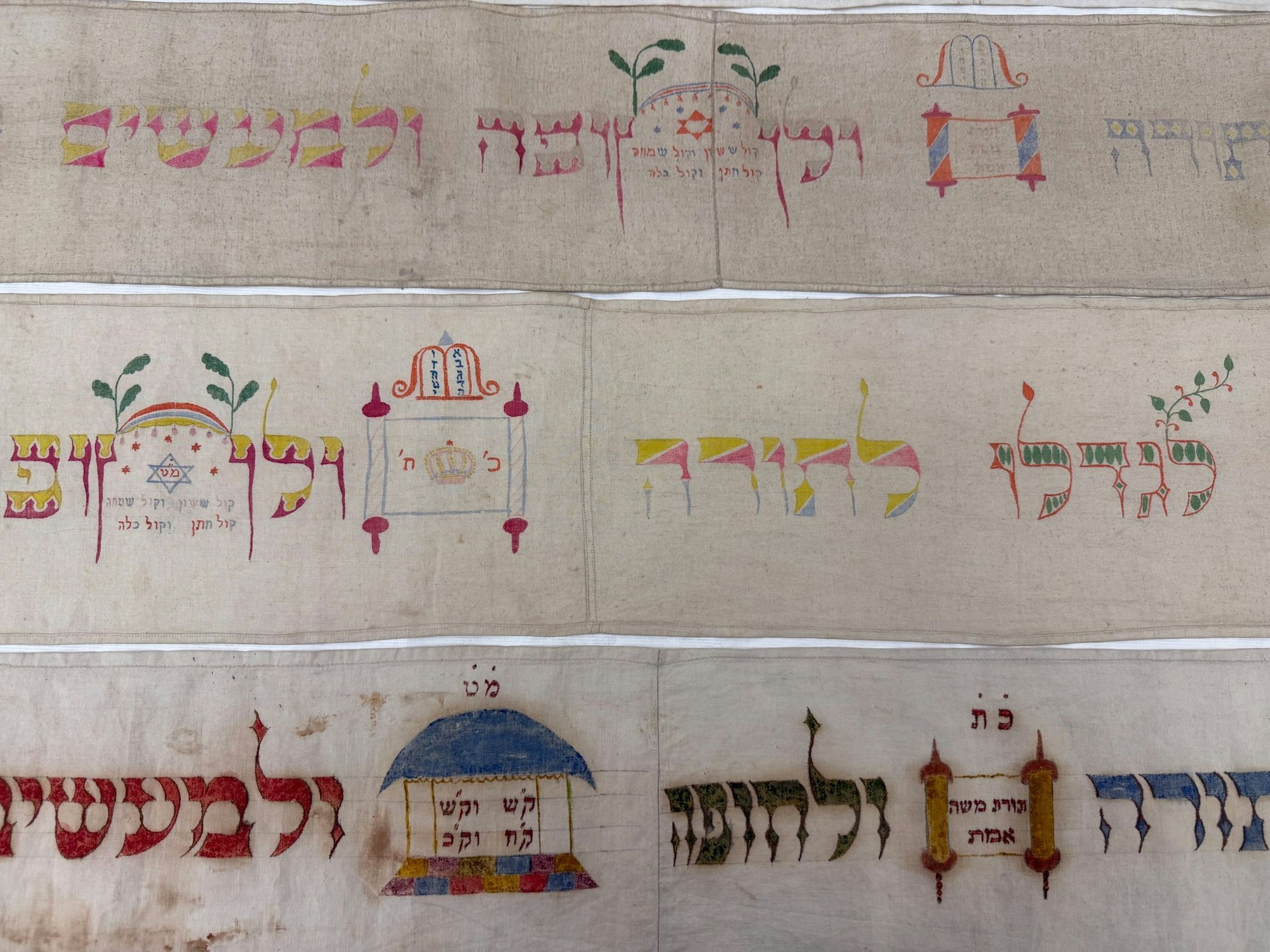 Auf den Torabändern befinden sich hebräische Schrift und Verzierungen.