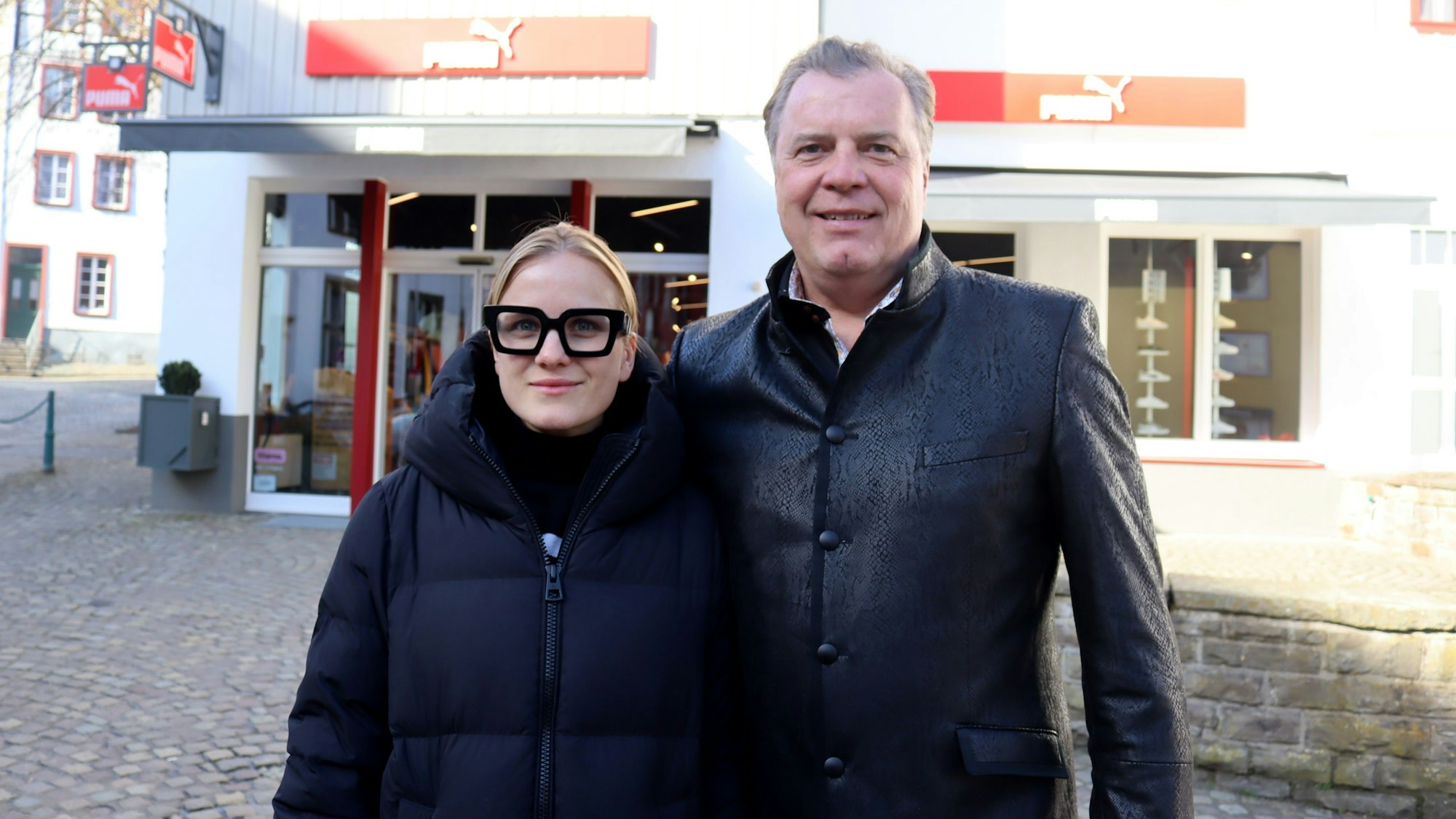 Julia und Marc Brucherseifer stehen vor dem Puma Store, darüber befindet sich die Zentrale des City Outlets.