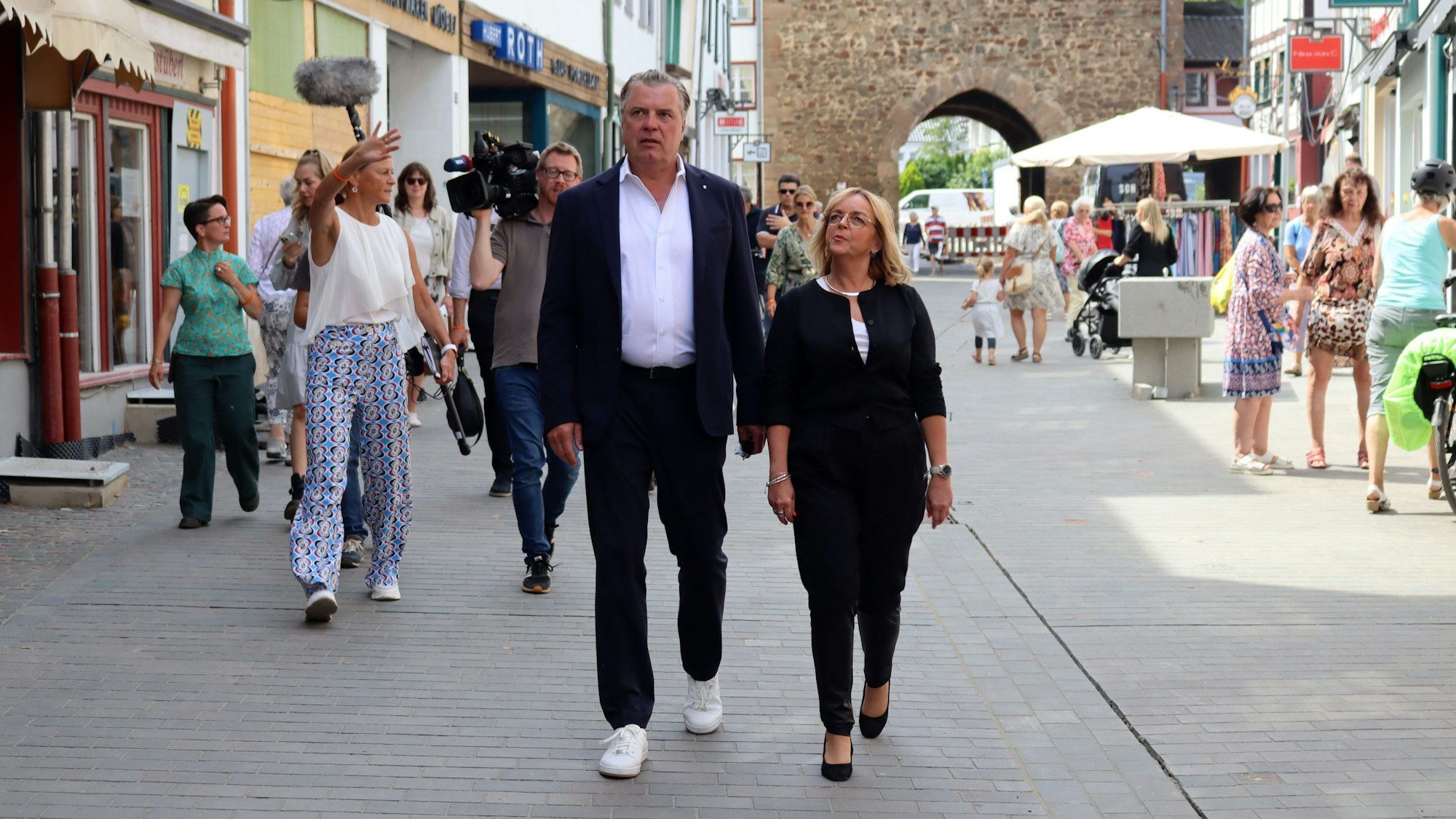 Marc Brucherseifer und Sabine Preiser-Marian gehen über die neu gepflasterte Orchheimer Straße. Im Hintergrund geht ein Kamerateam.