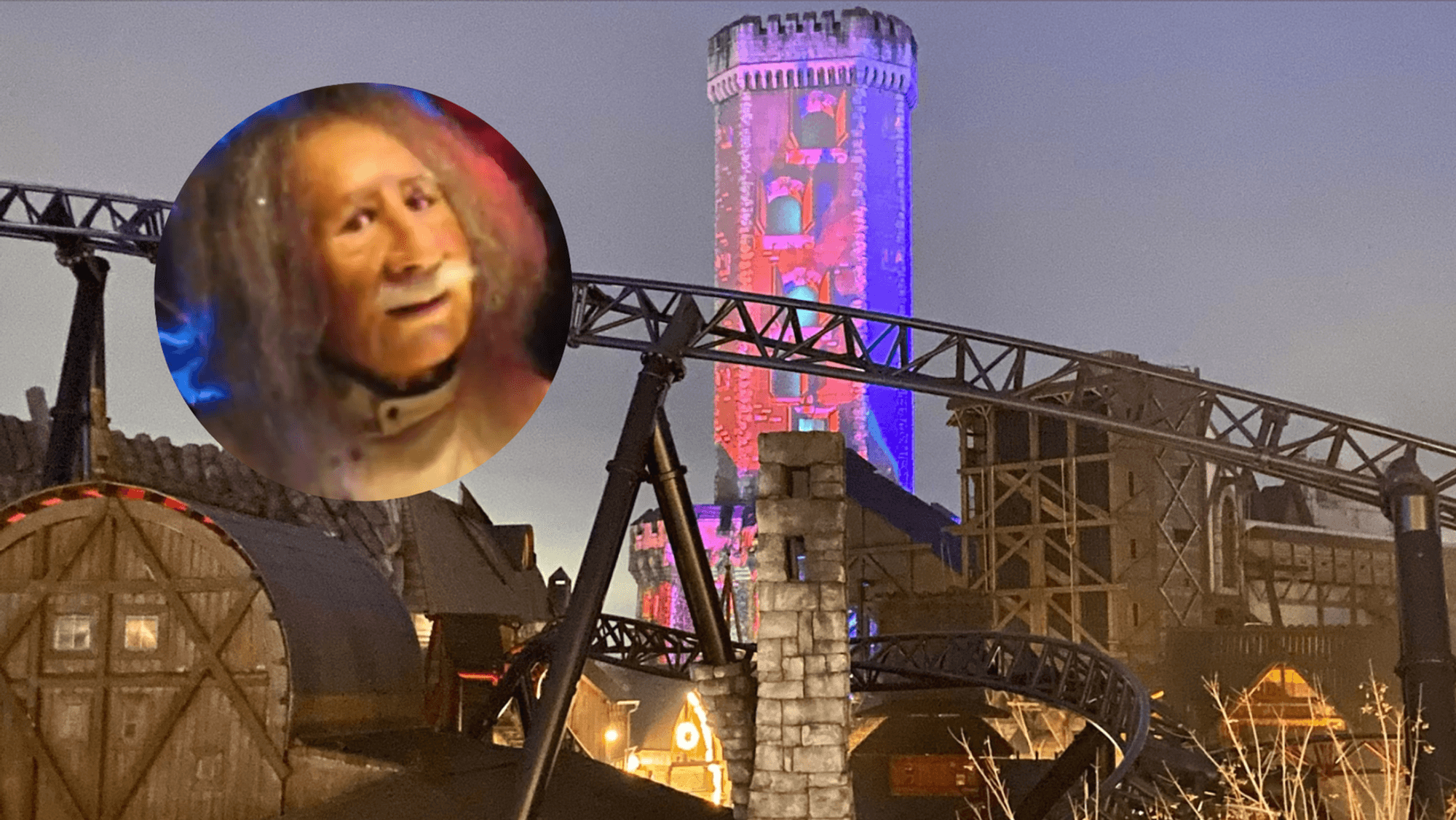 Ein geheimnisvoller Turm ragt über das Phantasialand, im Vordergrund sieht man eine Achterbahn in der Dämmerung.