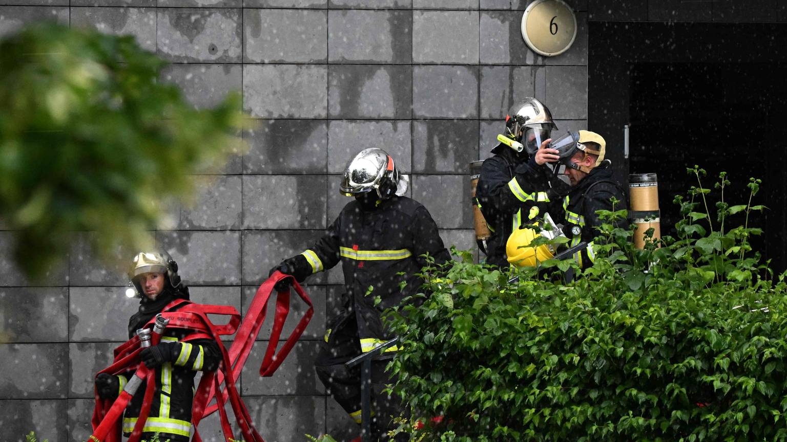 Feuerwehrleute verlassen ein Gebäude, nachdem sie ein Feuer gelöscht haben, das in der Nacht zum 6. Juni 2025 in einem Wohnhaus in Reims ausgebrochen war.