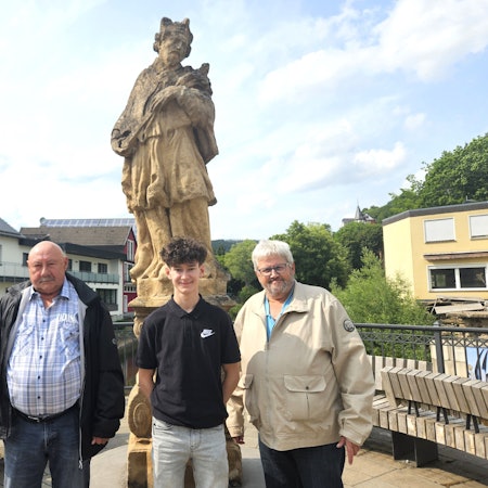 Franz-Albert Heinen, Christian Baran und Wolfgang Pommer (v.l.) stehen vor der Nepomuk-Statue am Zusammenfluss von Urft und Olef.
