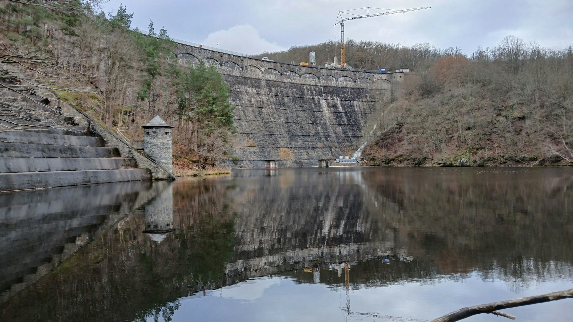 Die Aufnahme zeigt einen Kran, der sich im Wasser eines Stausees spiegelt.