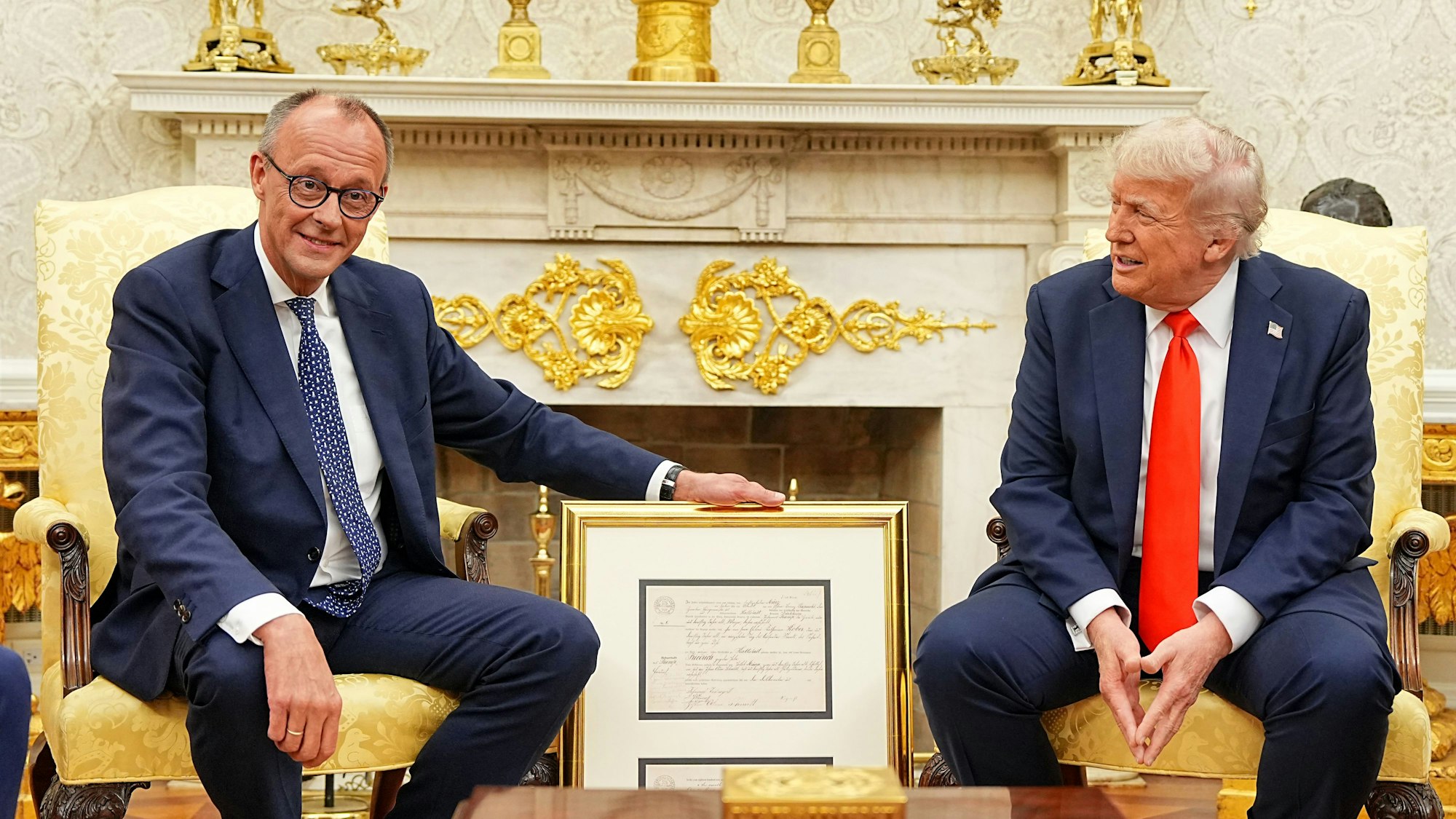 US-Präsident Donald Trump (r) empfängt Bundeskanzler Friedrich Merz (CDU) im Oval Office im Weißen Haus. Merz überreichte ein Faksimile der Geburtsurkunde (oben deutsche, unten englische Fassung) von Friedrich (später Frederick) Trump, Großvater von US-Präsident Donald Trump als Gastgeschenk.