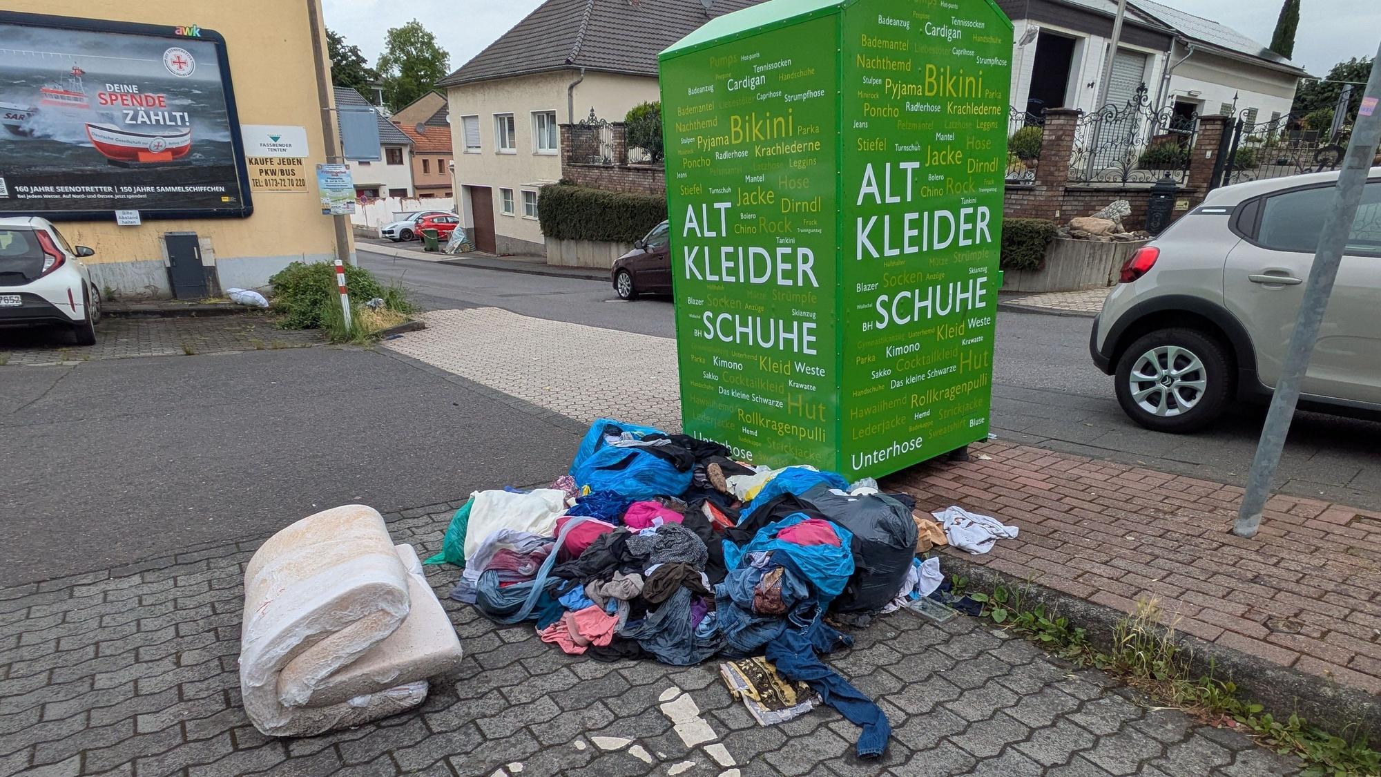 Kleider und eine alte Matratze vor einem Altkleidercontainer in Alfter-Ort.