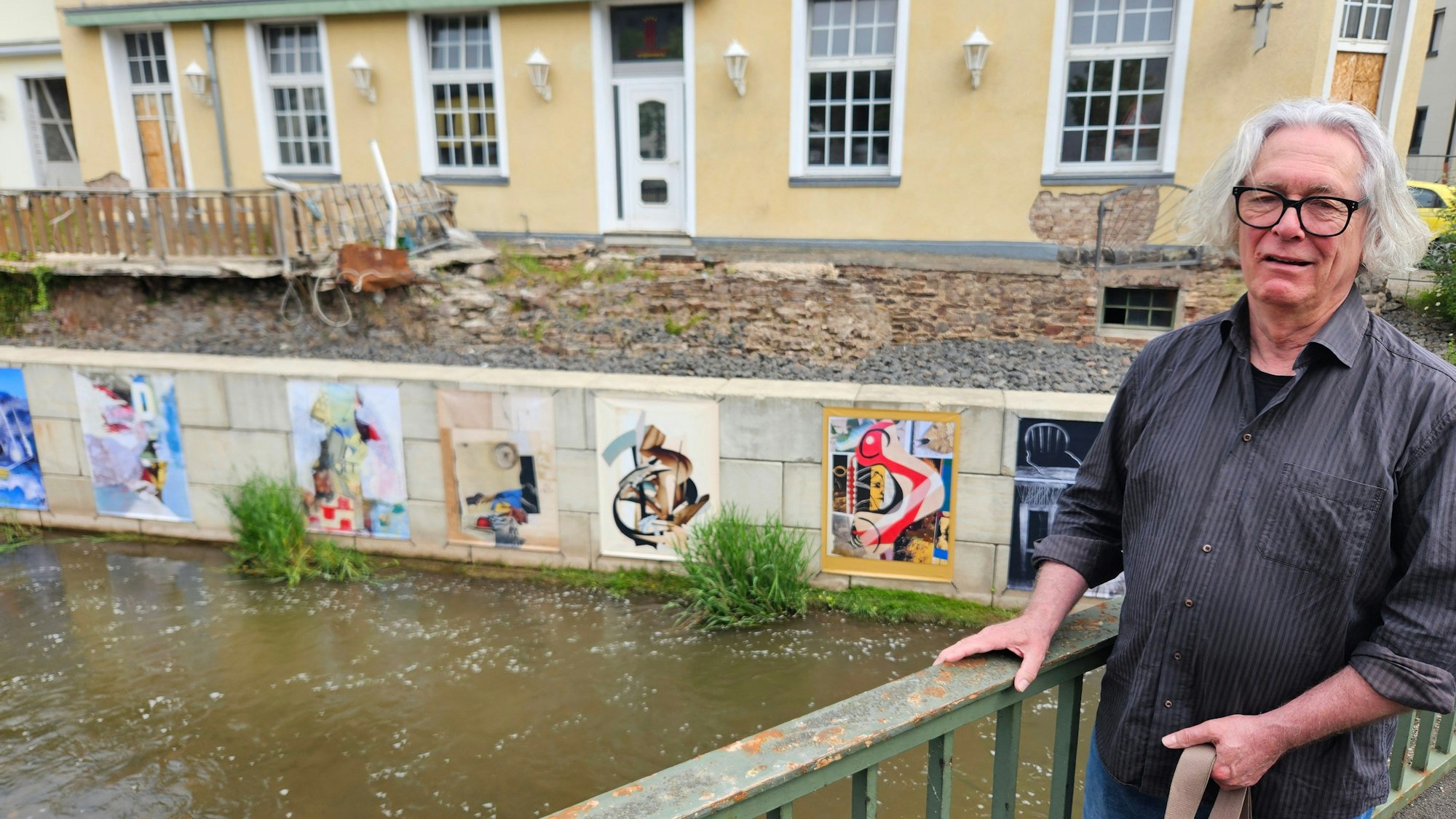 Jürgen A. Roder steht an einem Geländer. Im Hintergrund sind einige Kunstwerke zu sehen.
