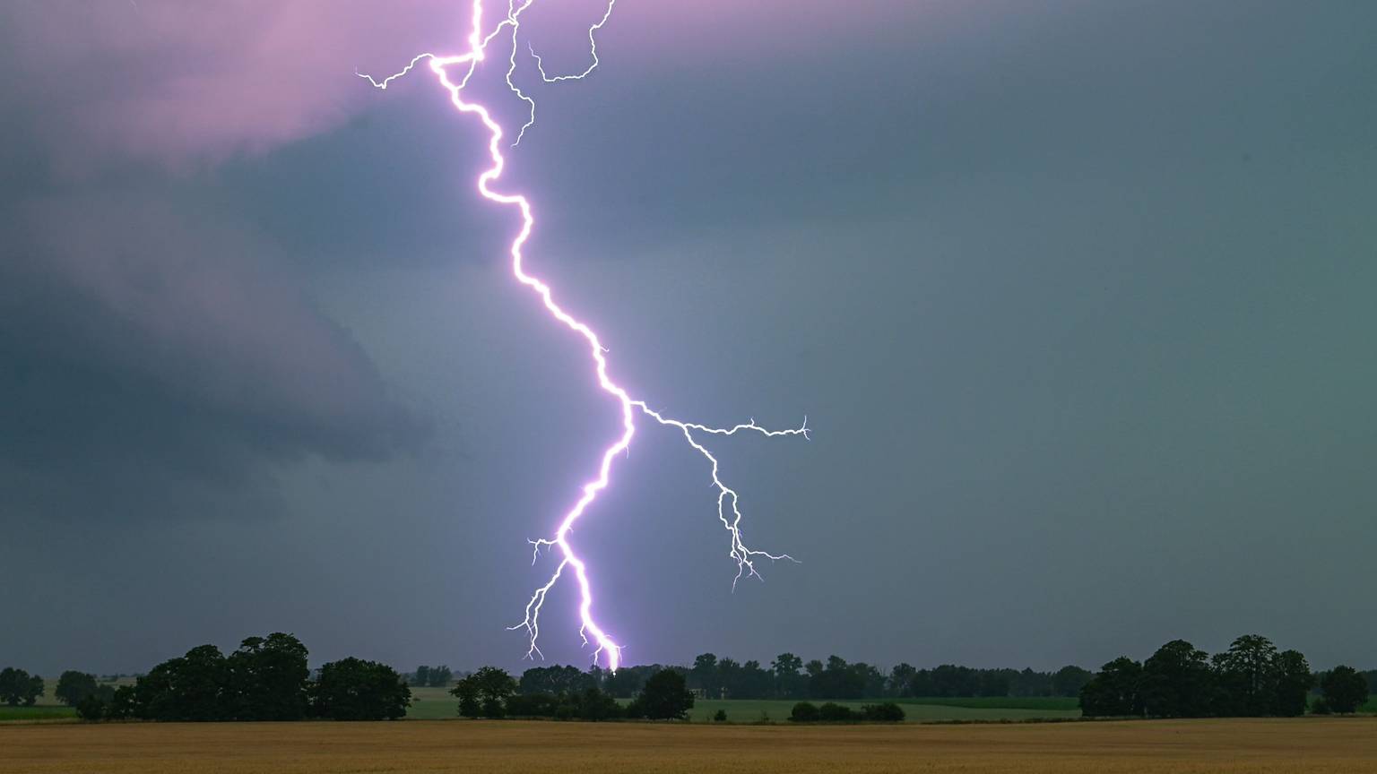 ARCHIV - 21.06.2024, Brandenburg, Heinersdorf: Ein Blitz leuchtet über einer Landschaft auf. (zu dpa: «Blitz, Donner und Schauer in Berlin und Brandenburg») Foto: Patrick Pleul/dpa +++ dpa-Bildfunk +++