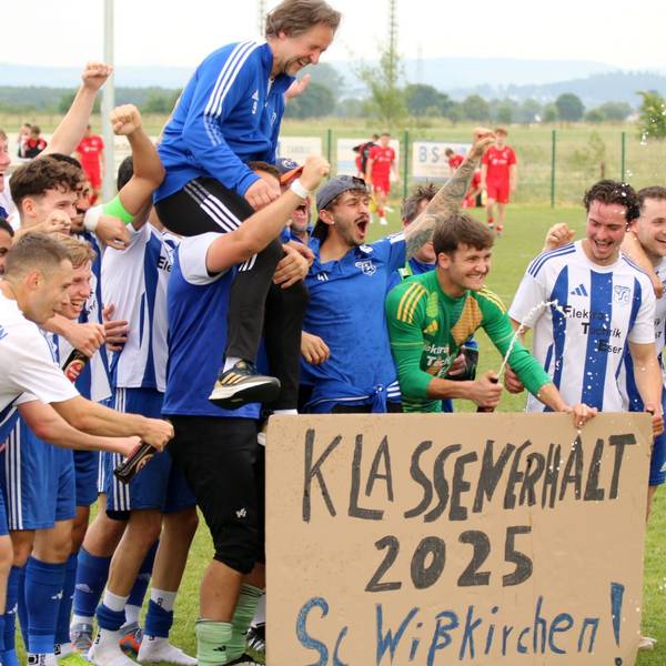 Die Wißkirchener Spieler stehen hinter einer Pappe, auf der "Klassenerhalt 2025" steht. Ihren Trainer Horst Bartz tragen sie auf Schultern.