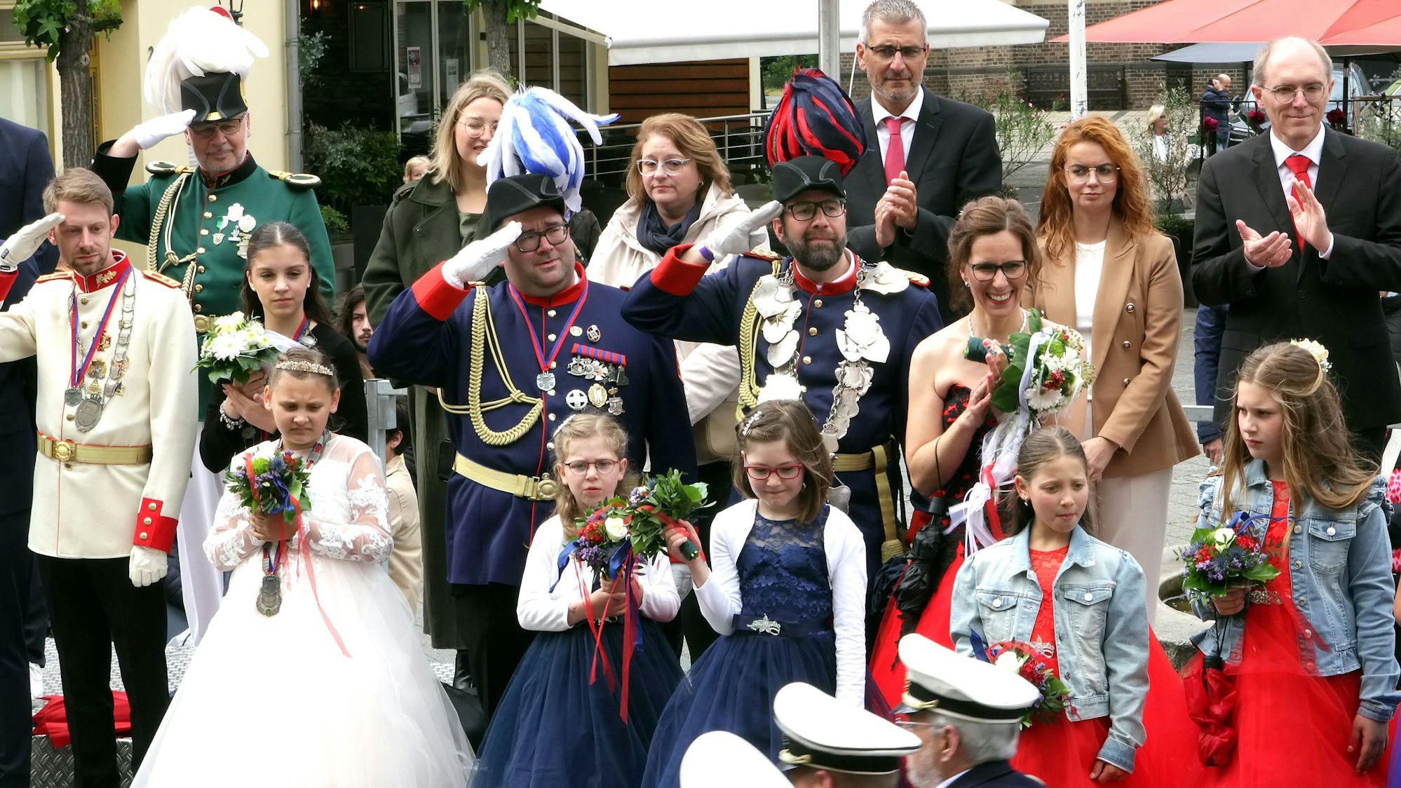 Zu sehen sind Schützen unterschiedlichen Alters und Geschlechts in Uniform und Kleidern.