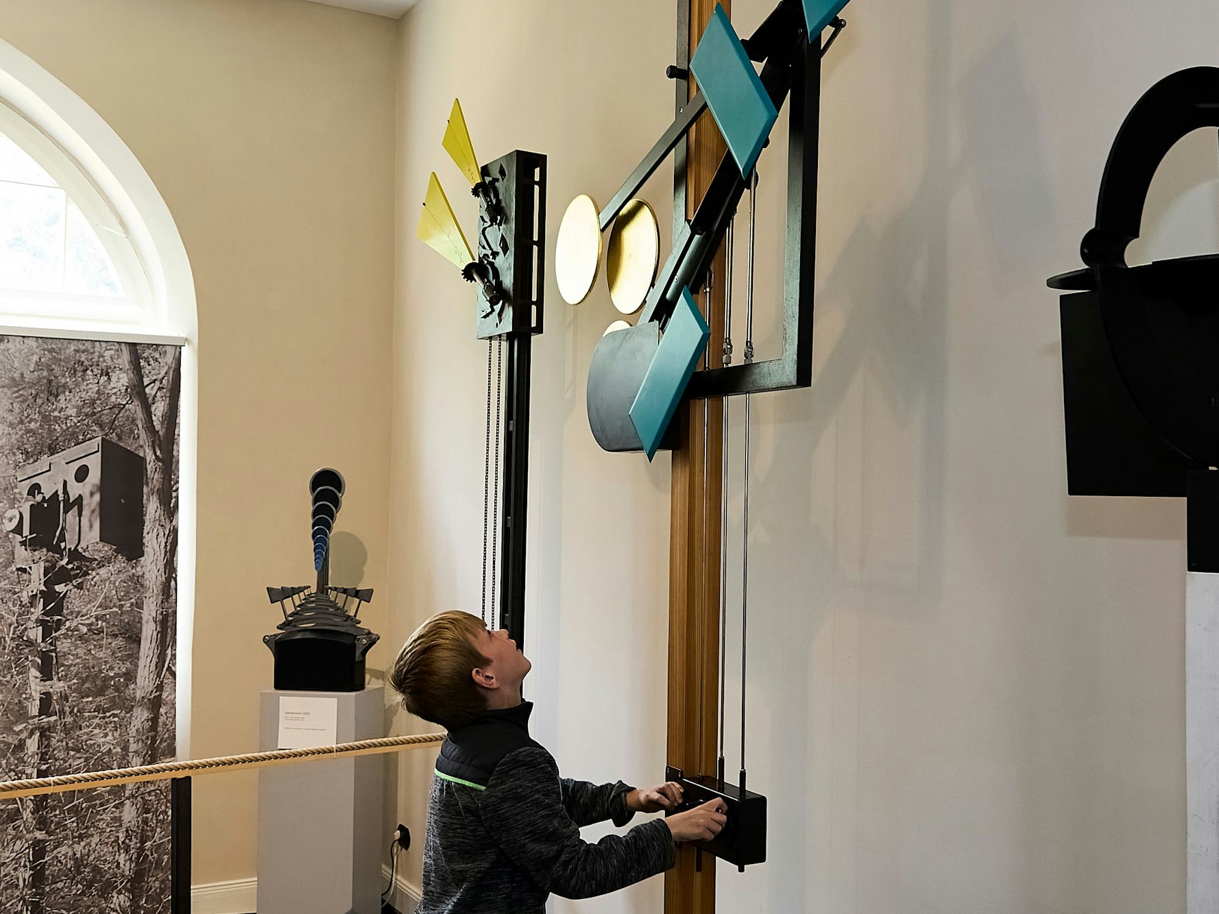 Ein Junge erkundet in einer Ausstellung eine Apparatur.