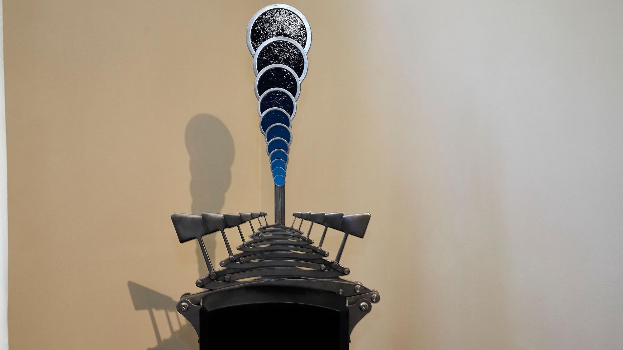 Das Bild zeigt ein Kunstwerk, das aus mehreren blauen Kreisen und Metall-Hammern besteht.