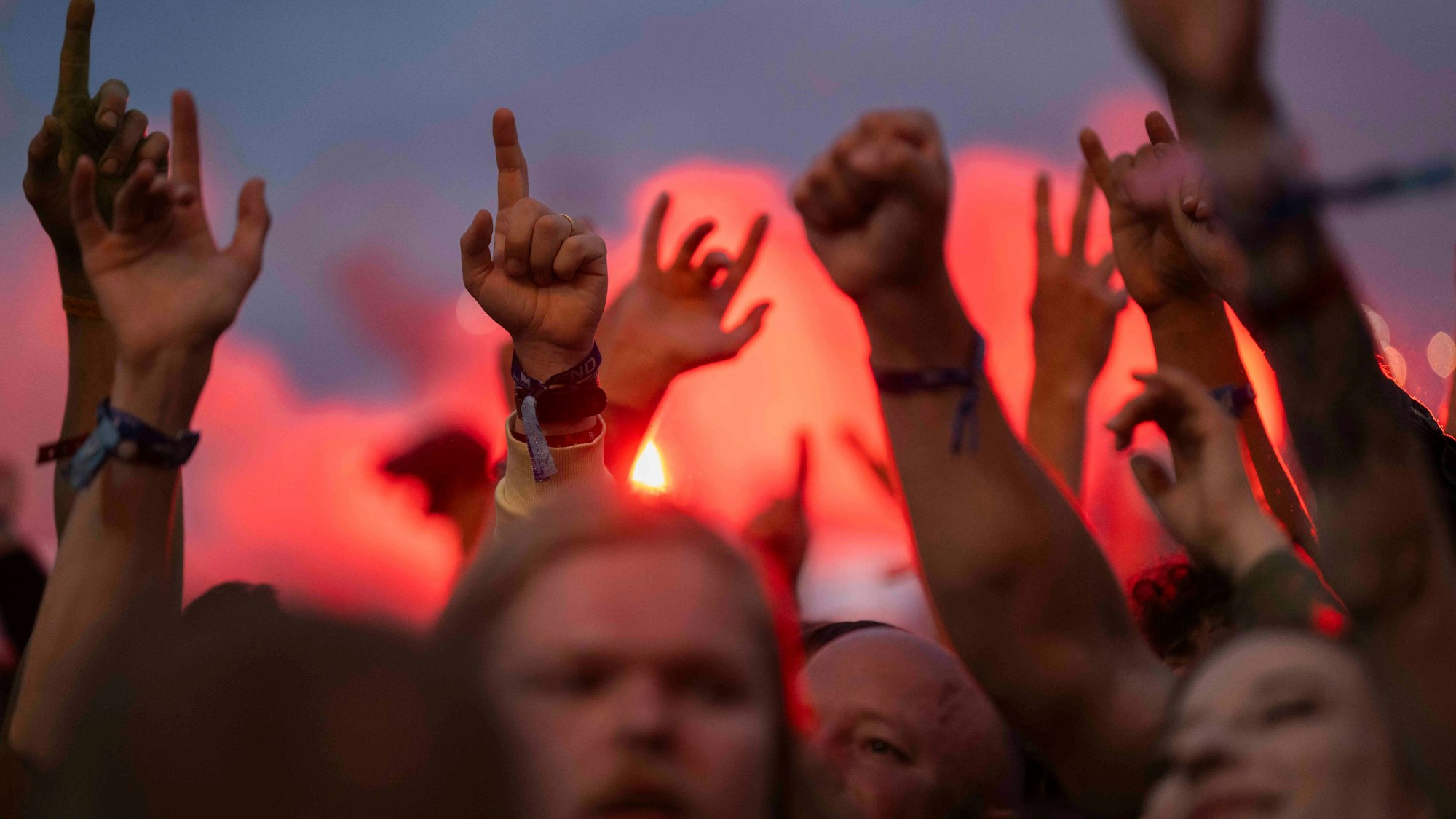 Das Bild zeigt mehrere in die Luft gehobenen Hände vor einem Sonnenuntergang.