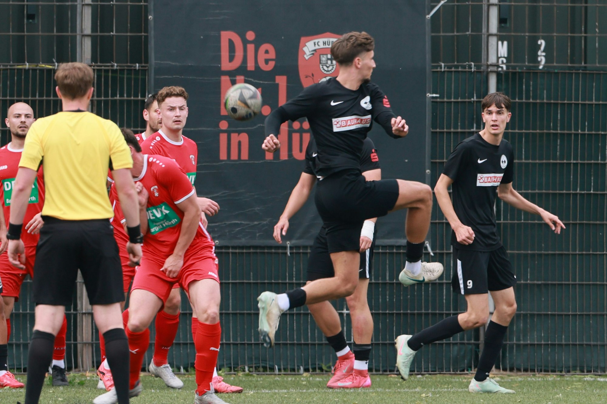 Das Foto zeigt einen Fußballer im dunklen Trikot von Frechen 20, der den Ball artistisch in den Hürther Strafraum weiterleitet.