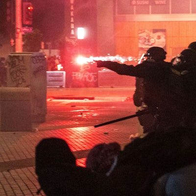 09.06.2025, USA, Los Angeles: Polizisten gehen während der Proteste gegen die Razzien der Trump-Regierung gegen Einwanderer in Los Angeles vor Geschossen in Deckung. Foto: Ethan Swope/FR171736 AP/dpa +++ dpa-Bildfunk +++