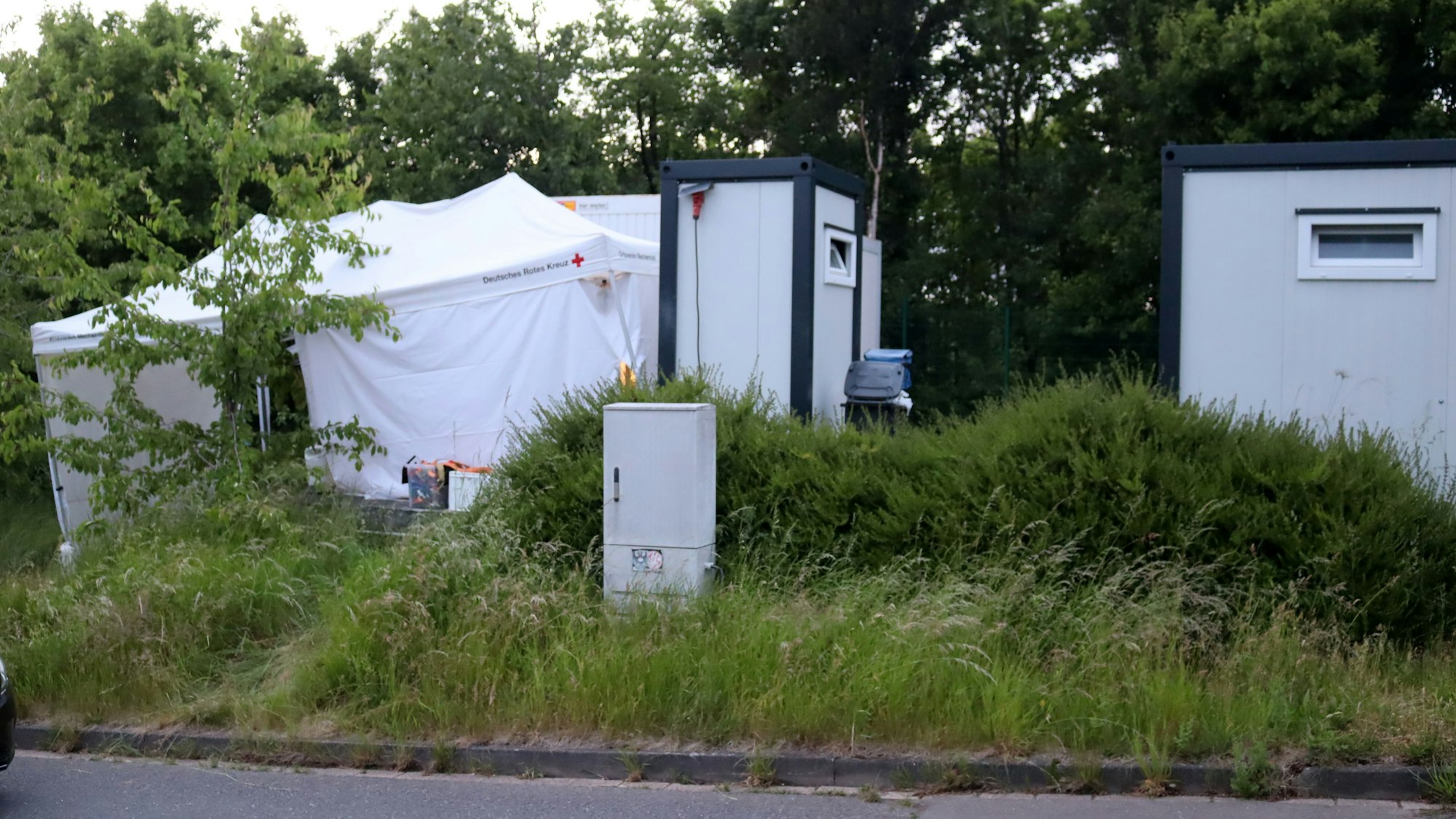Das Bild zeigt zwei Wohncontainer und ein weißes Zelt des DRK.