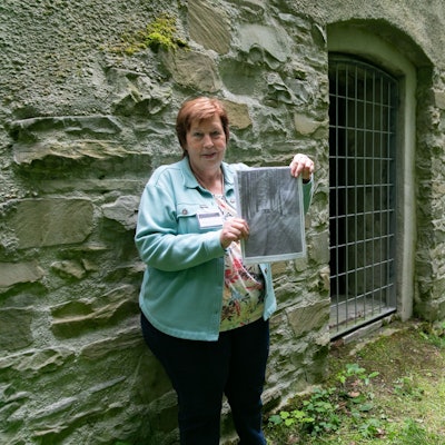 Eine Frau hält ein historisches Foto in den Händen.