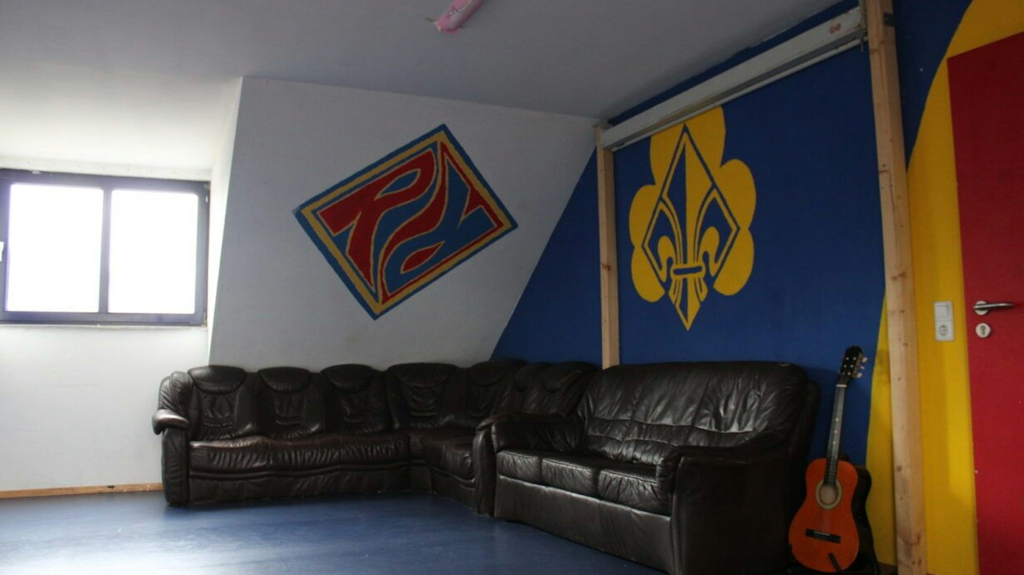 Über eine Sofaecke sind die Wappen der Pfadfinder an die Wand gemalt.