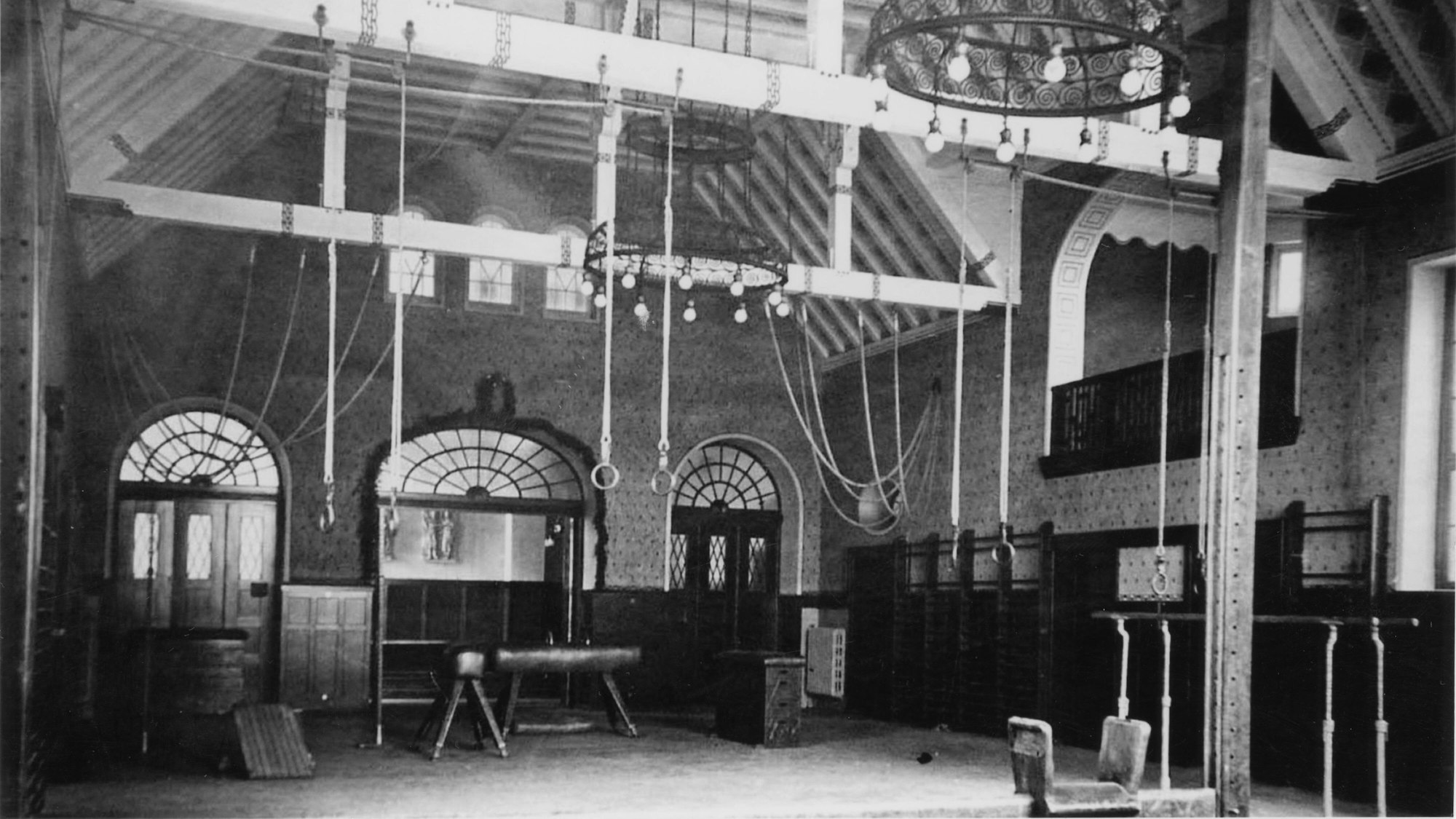 Eine alte Turnhalle um 1920, mit Pferd, Barren, Kasten und Seilen.