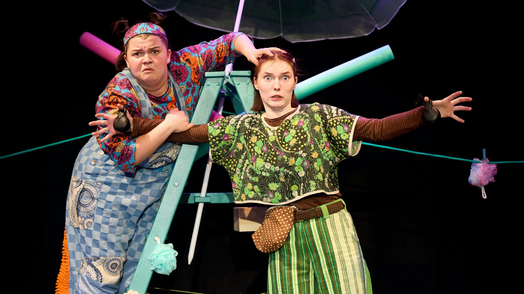 Zwei Frauen stehen kostümiert auf einer Bühne.
