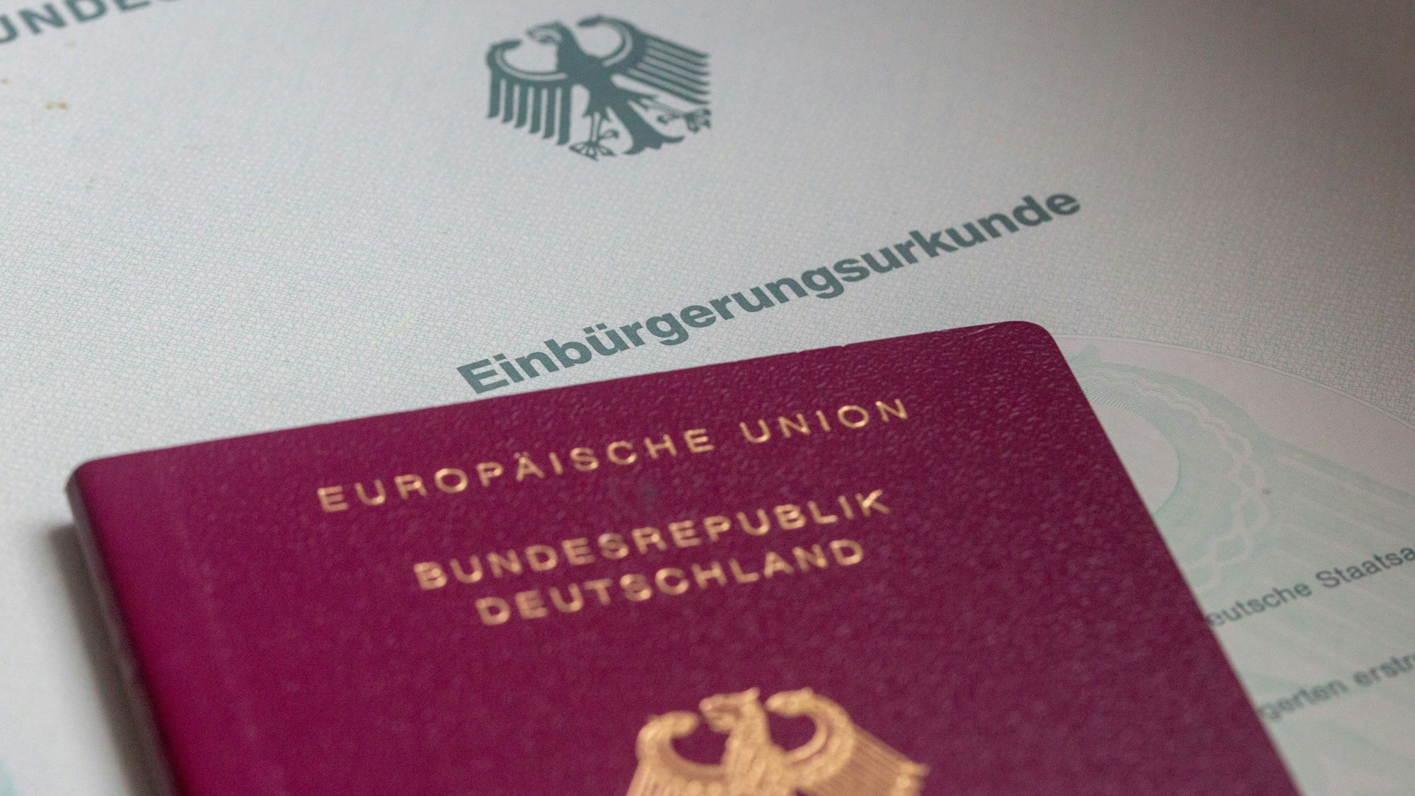 Eine Einbürgerungsurkunde der Bundesrepublik Deutschland und ein deutscher Reisepass liegen auf einem Tisch.