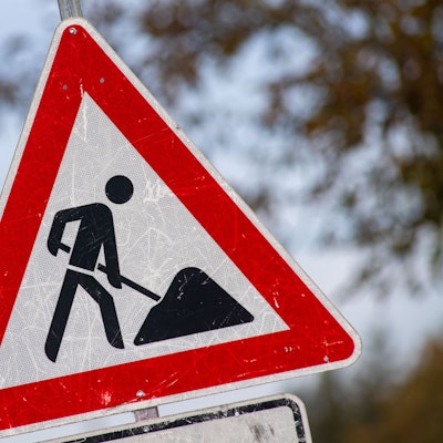 Das Bild zeigt ein zerkratztes Schild mit dem Piktogramm eines Bauarbeiters zur Beschilderung einer Baustelle.