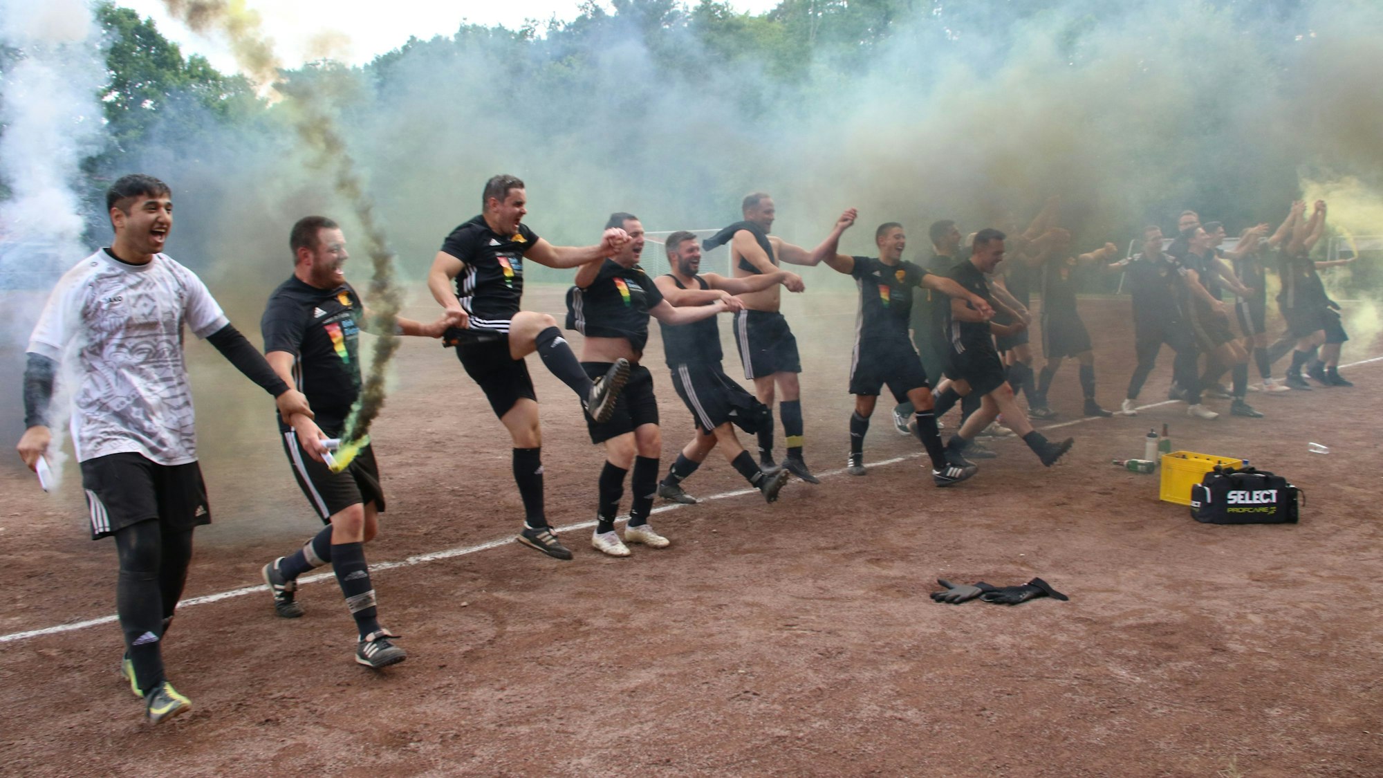Die Firmenicher Spieler bilden eine Reihe und jubeln über den Aufstieg. Schwarz-gelber Rauch kommt aus Rauchbomben.