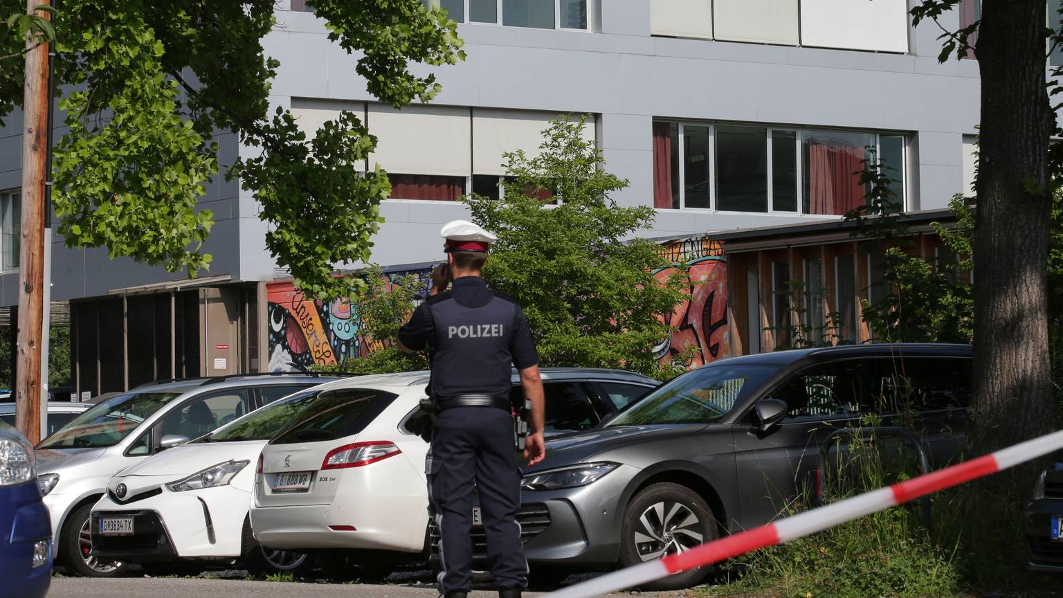 Ein Polizeibeamter telefoniert vor dem Schulgebäude. Ein 21-Jähriger aus dem Raum Graz hat nach Angaben der Behörden die tödlichen Schüsse an einem Gymnasium im österreichischen Graz abgegeben.