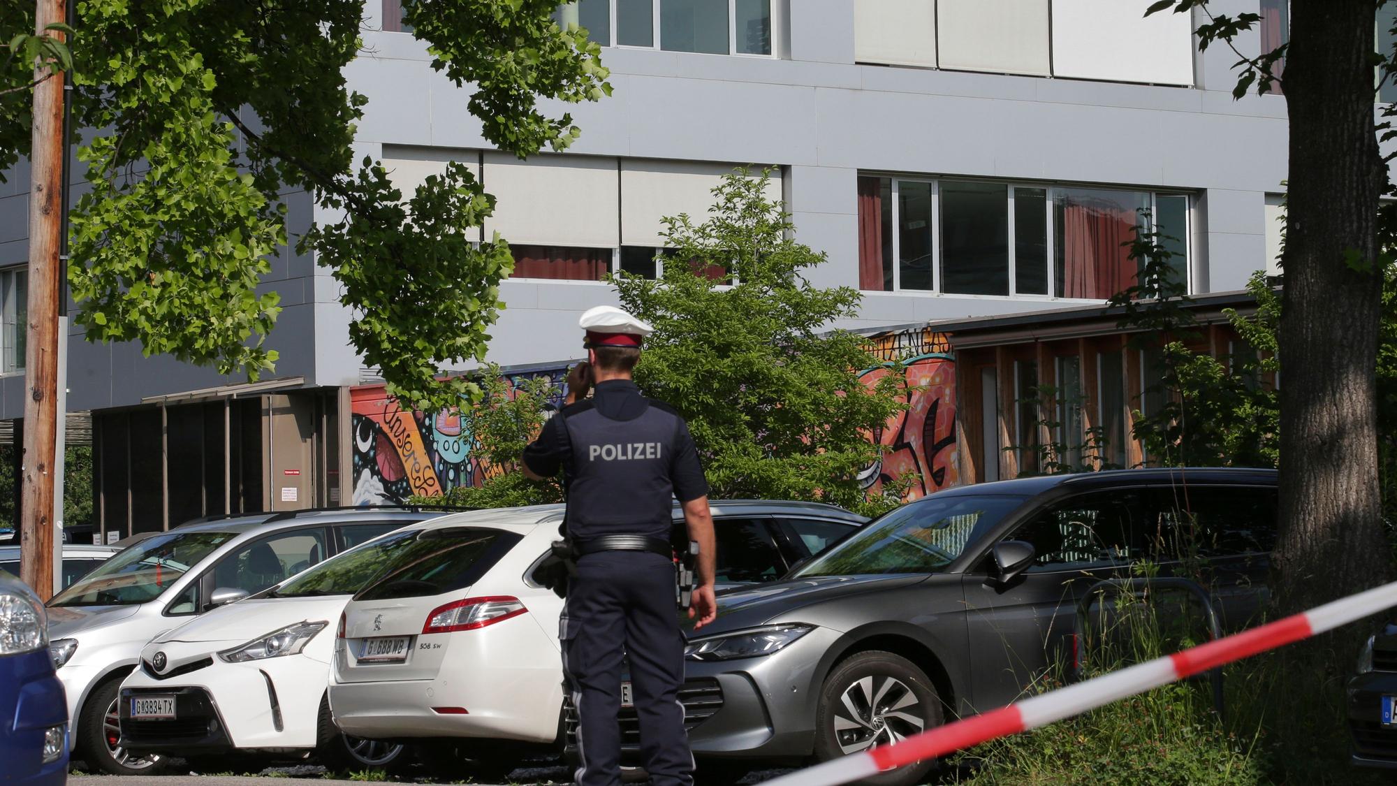 Ein Polizeibeamter telefoniert vor dem Schulgebäude. Ein 21-Jähriger aus dem Raum Graz hat nach Angaben der Behörden die tödlichen Schüsse an einem Gymnasium im österreichischen Graz abgegeben.