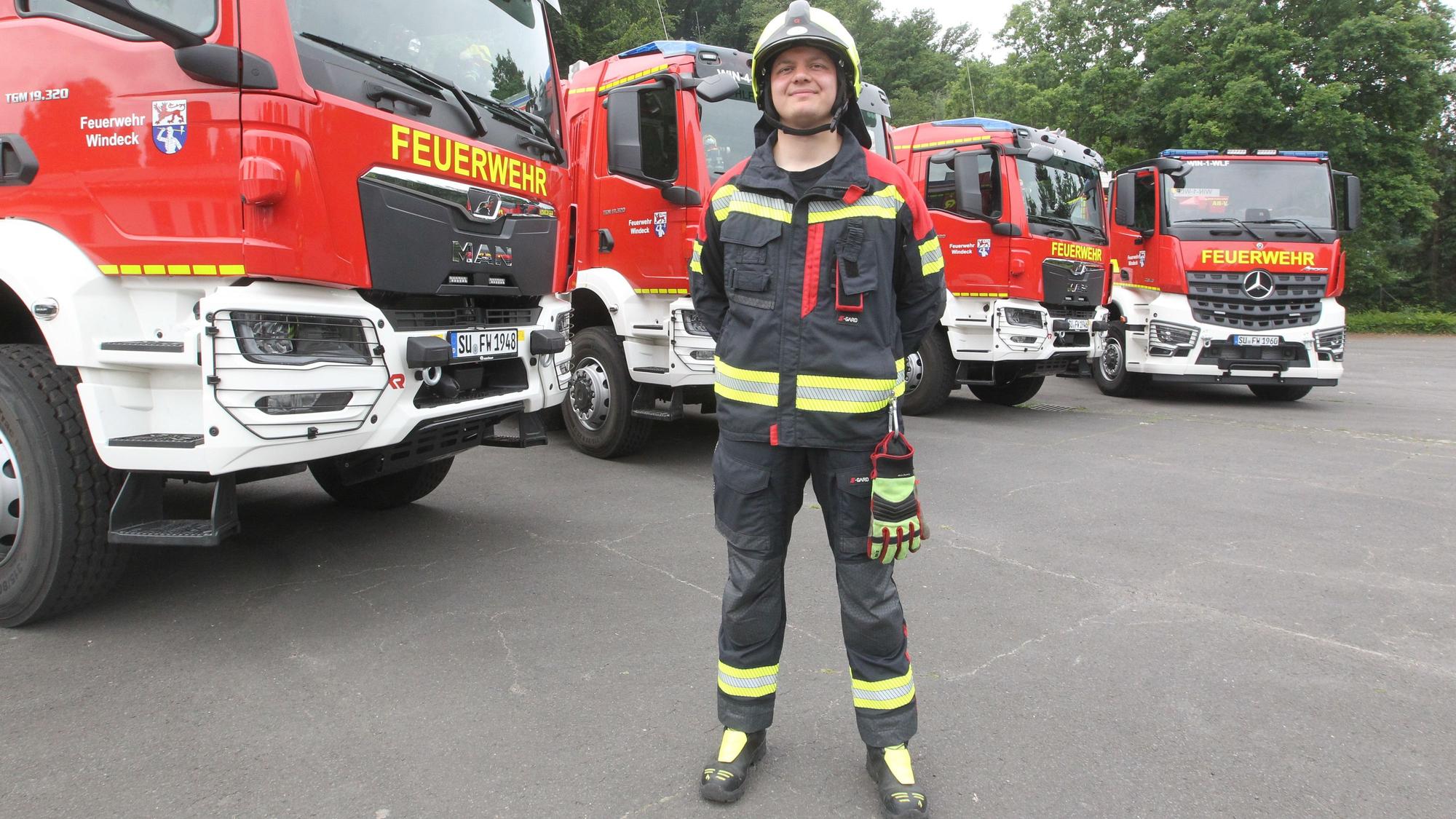 Feuerwehrmann Janos Voss in der modernen Montur vor den neuen Fahrzeugen.