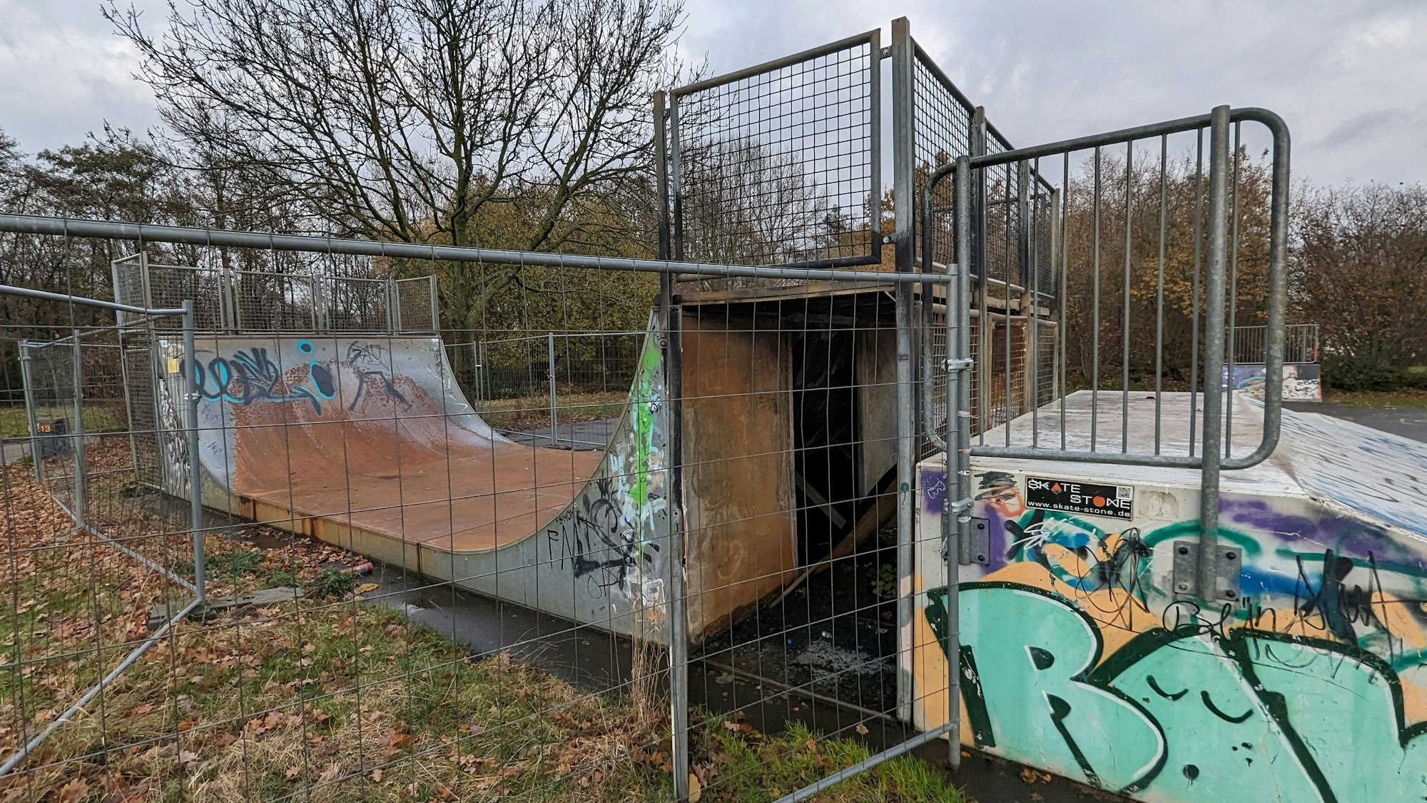 Das Foto zeigt die zerstörte Halfpipe hinter einem Bauzaun.