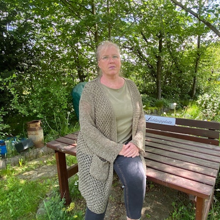 Sylvia Matuschek steht vor einer Sitzbank mit der Aufschrift „Lieblingsplatz“.