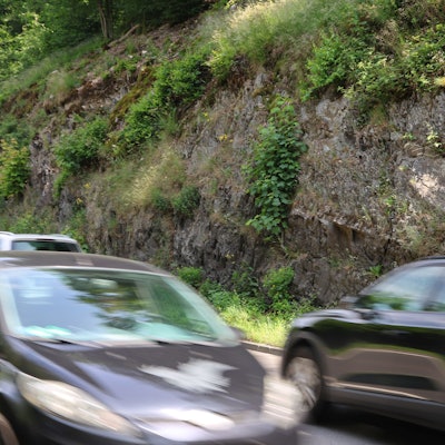 Eine Felswand, davor vorbeifahrende Autos.