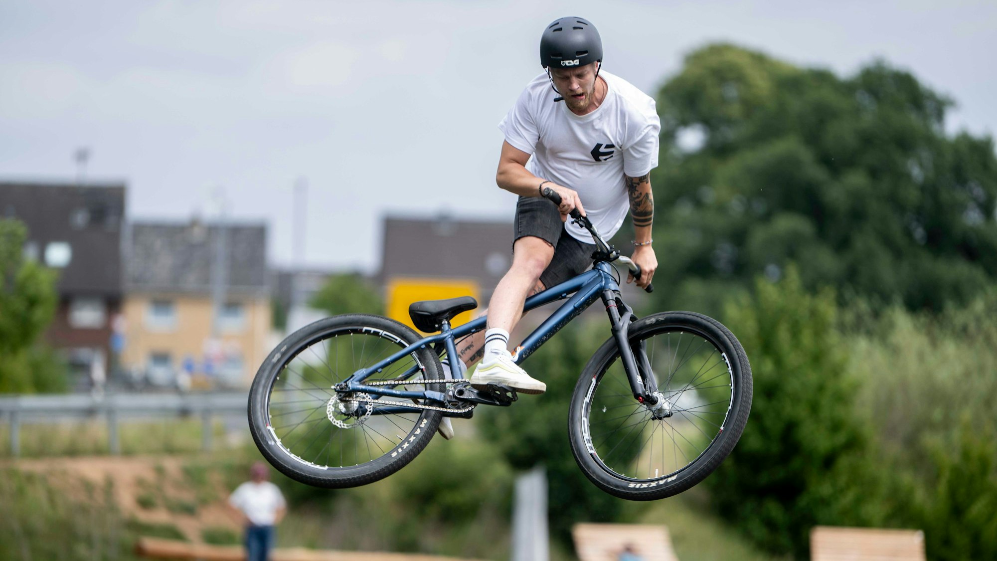 Ein junger Mann steht mit seinem Mountainbike quer in der Luft.