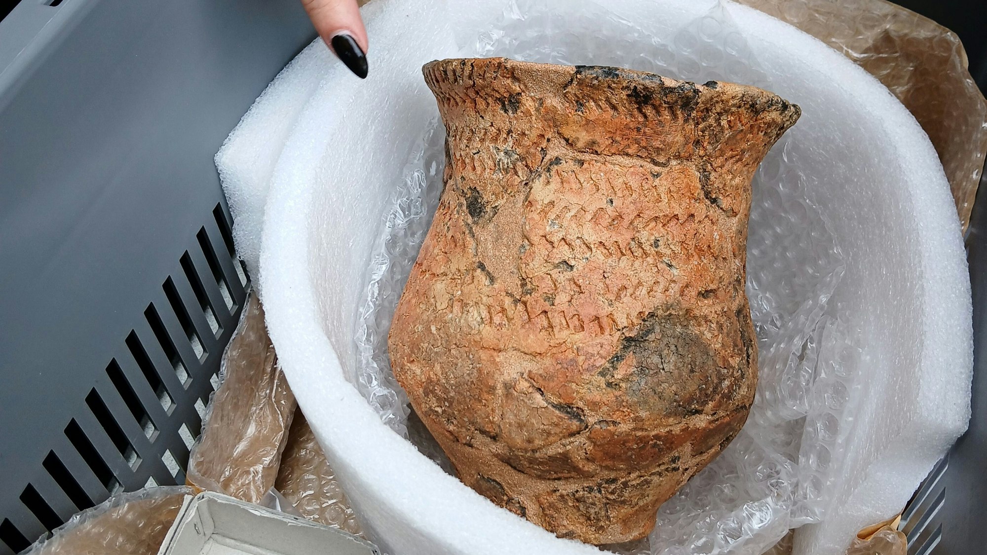 Das Bild zeigt ein historisches Gefäß in einem schützenden Behälter.