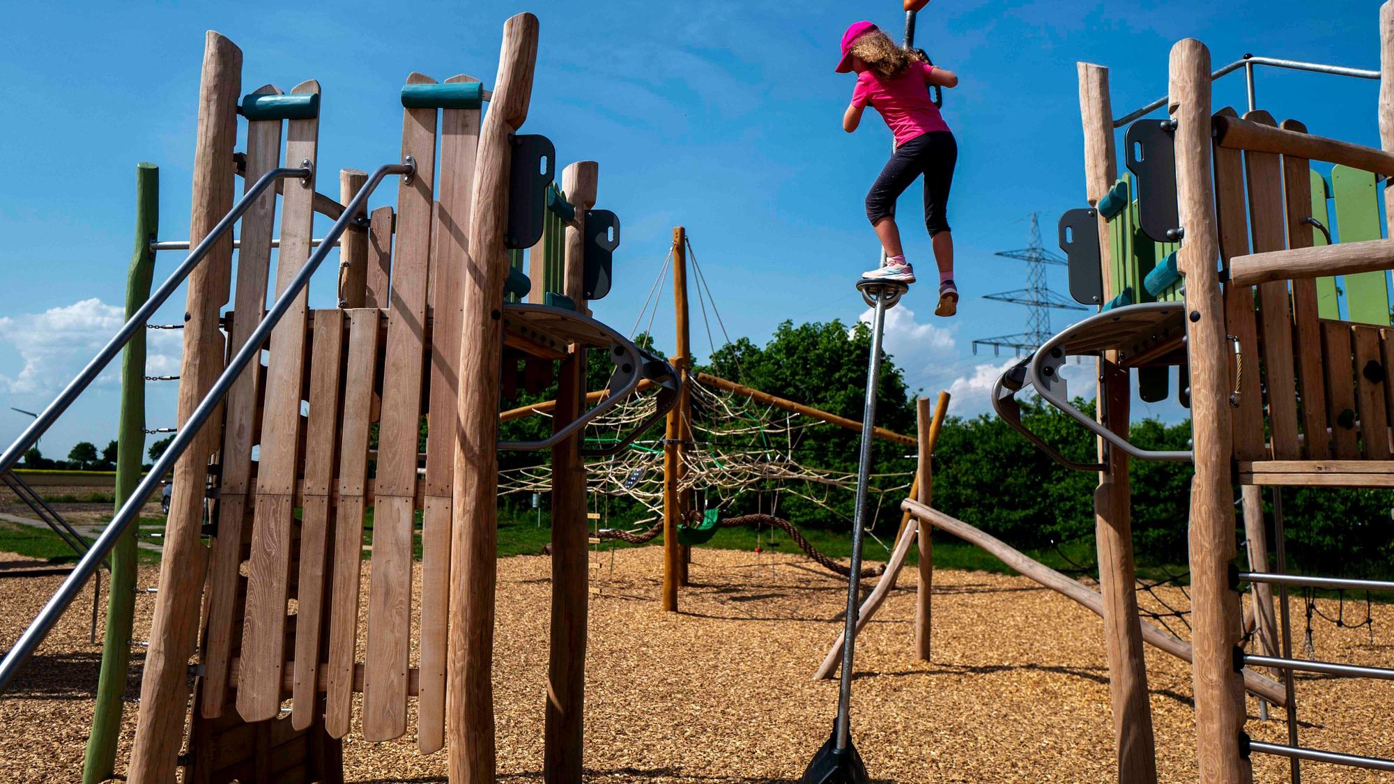 Das Bild zeigt ein Mädchen, das auf einem Spielplatz spielt. Es überwindet ein Hindernis mithilfe eines Pendels.