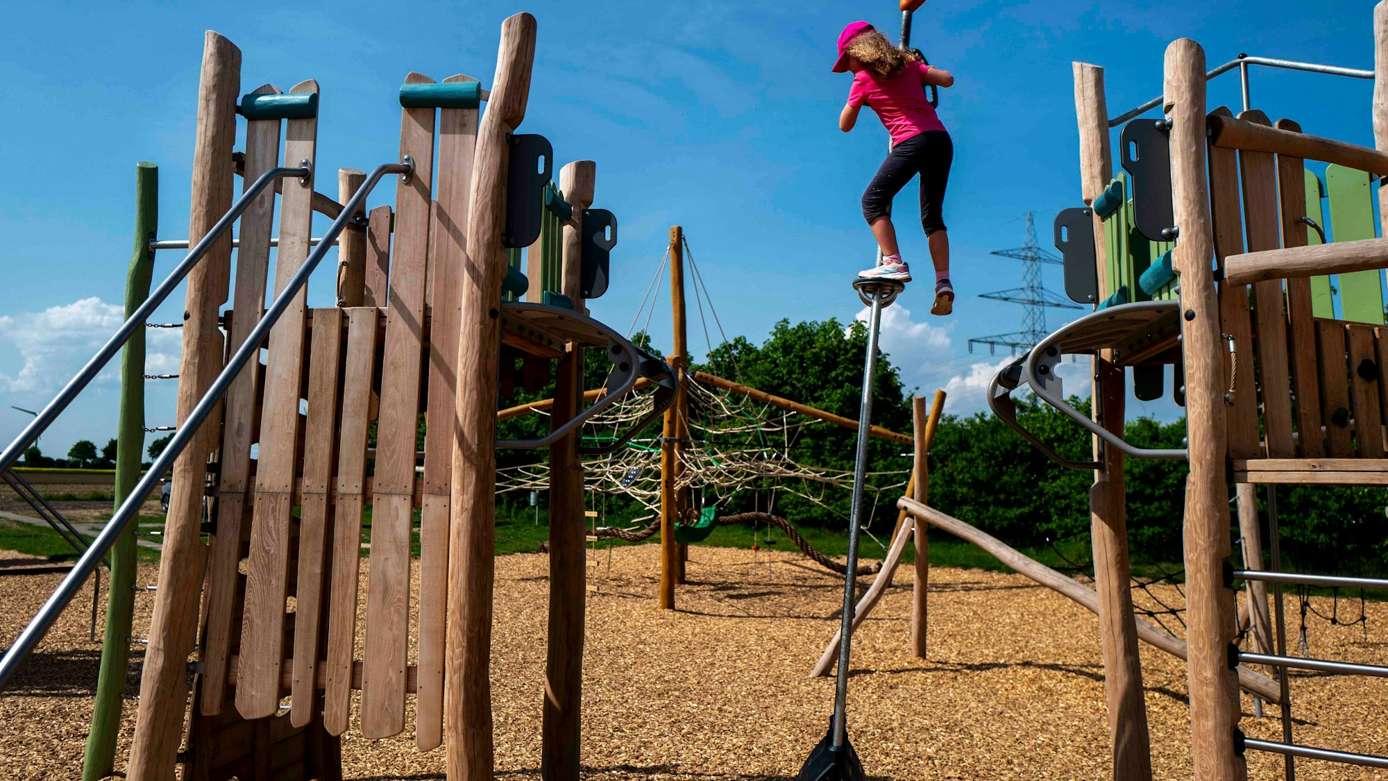 Das Bild zeigt ein Mädchen, das auf einem Spielplatz spielt. Es überwindet ein Hindernis mithilfe eines Pendels.