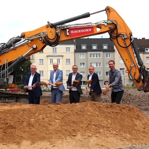 Moderne-Stadt-Geschäftsführer Andreas Röhrig, Baudezernent Markus Greitemann, Wohnungsgenossenschafts-Vorstand Christoph Moossen, Genossenschafts-Abteilungsleiter Neubau und Modernisierung Rainer Burkhardt sowie Architekt Tim Dückers (v.l.) beim gemeinsamen Spatenstich unter dem Bagger-Greifarm.